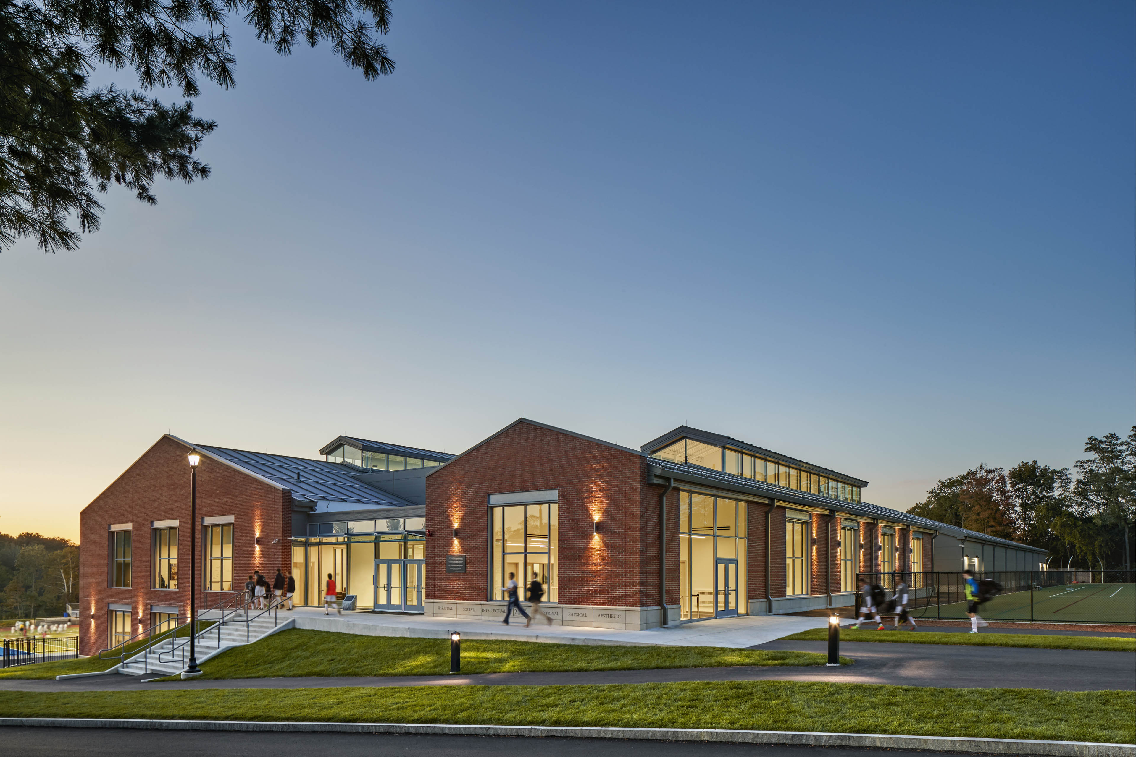 Exterior of school at dusk with green grass near drop off area and staircase near entrance