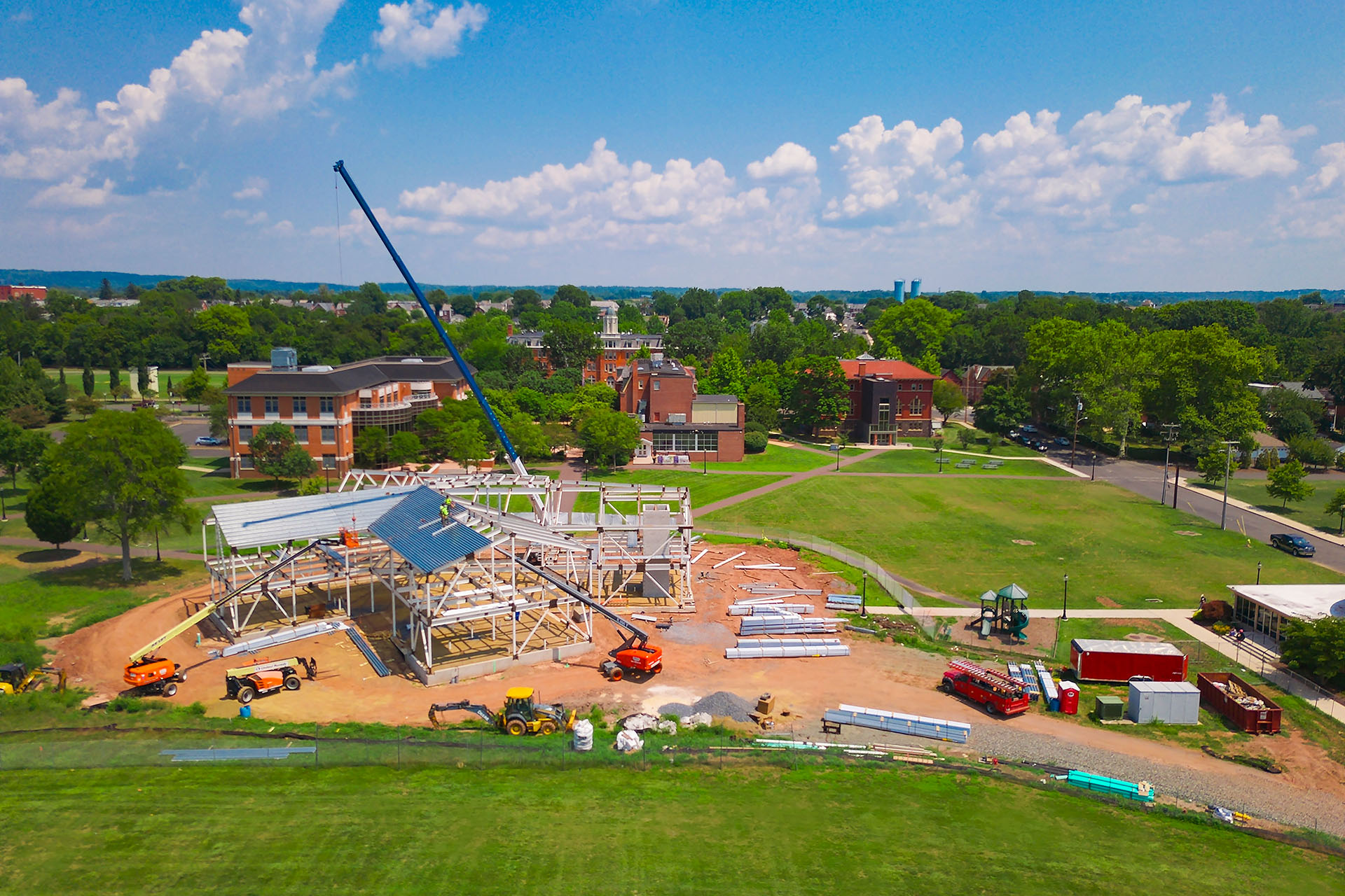 Active construction site for New Student Center at Perkiomen School in Pennsylvania. Blue sky on top with building nestled in to green field with bushy trees surrounding 