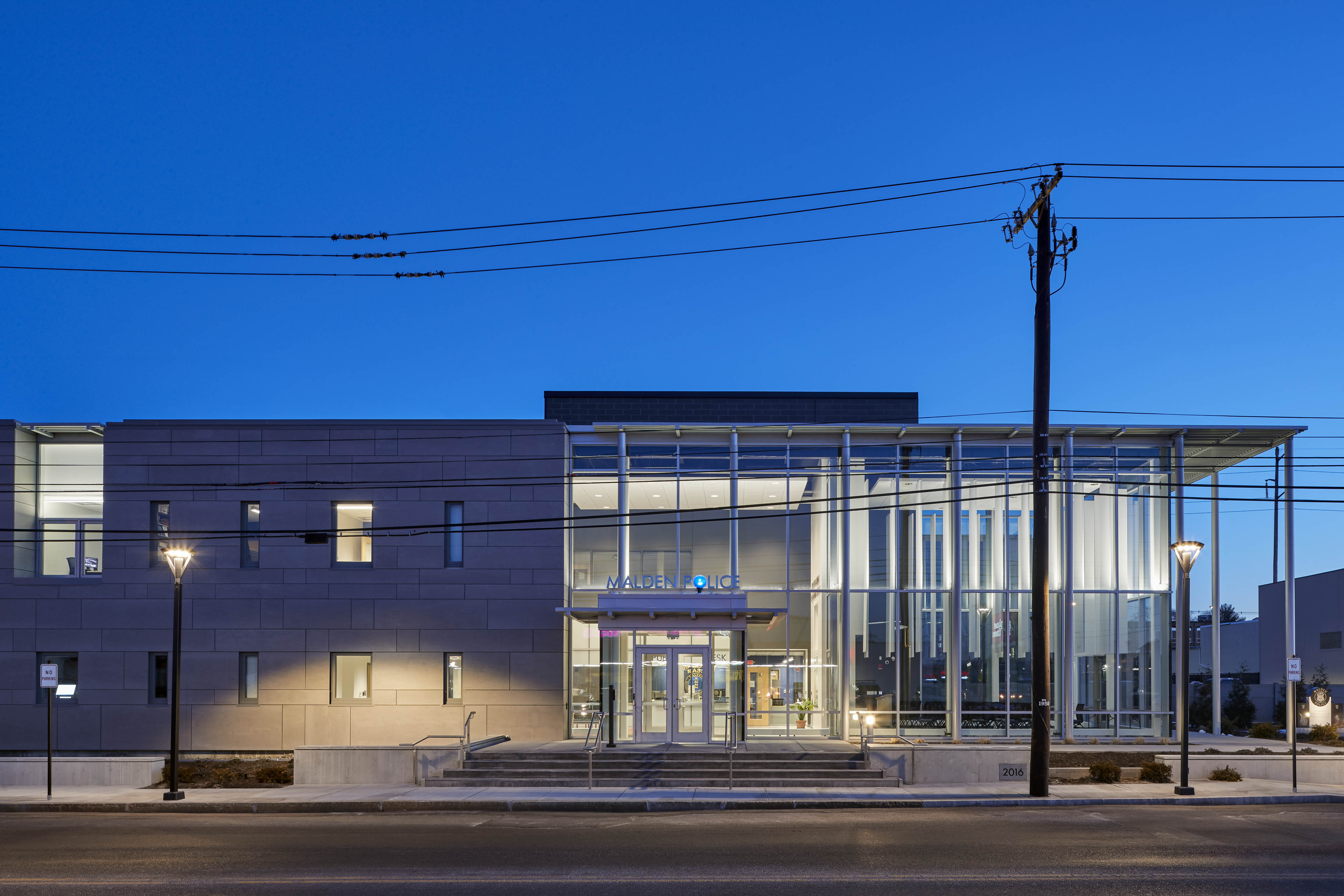 View from street at dawn, right side of building has floor to ceiling windows