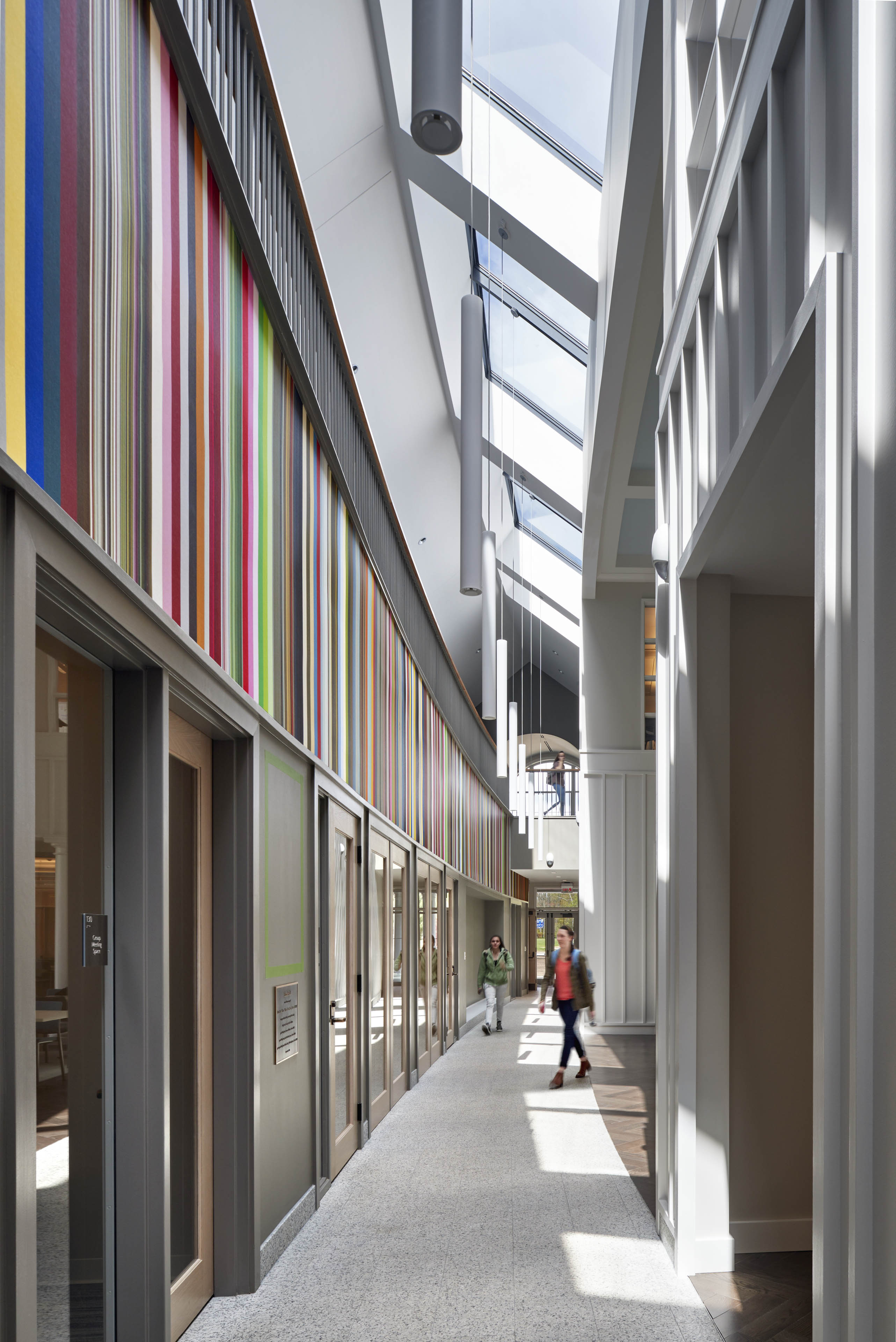 Interior corridor with students walking into classrooms, bright colored striping on wall to the left