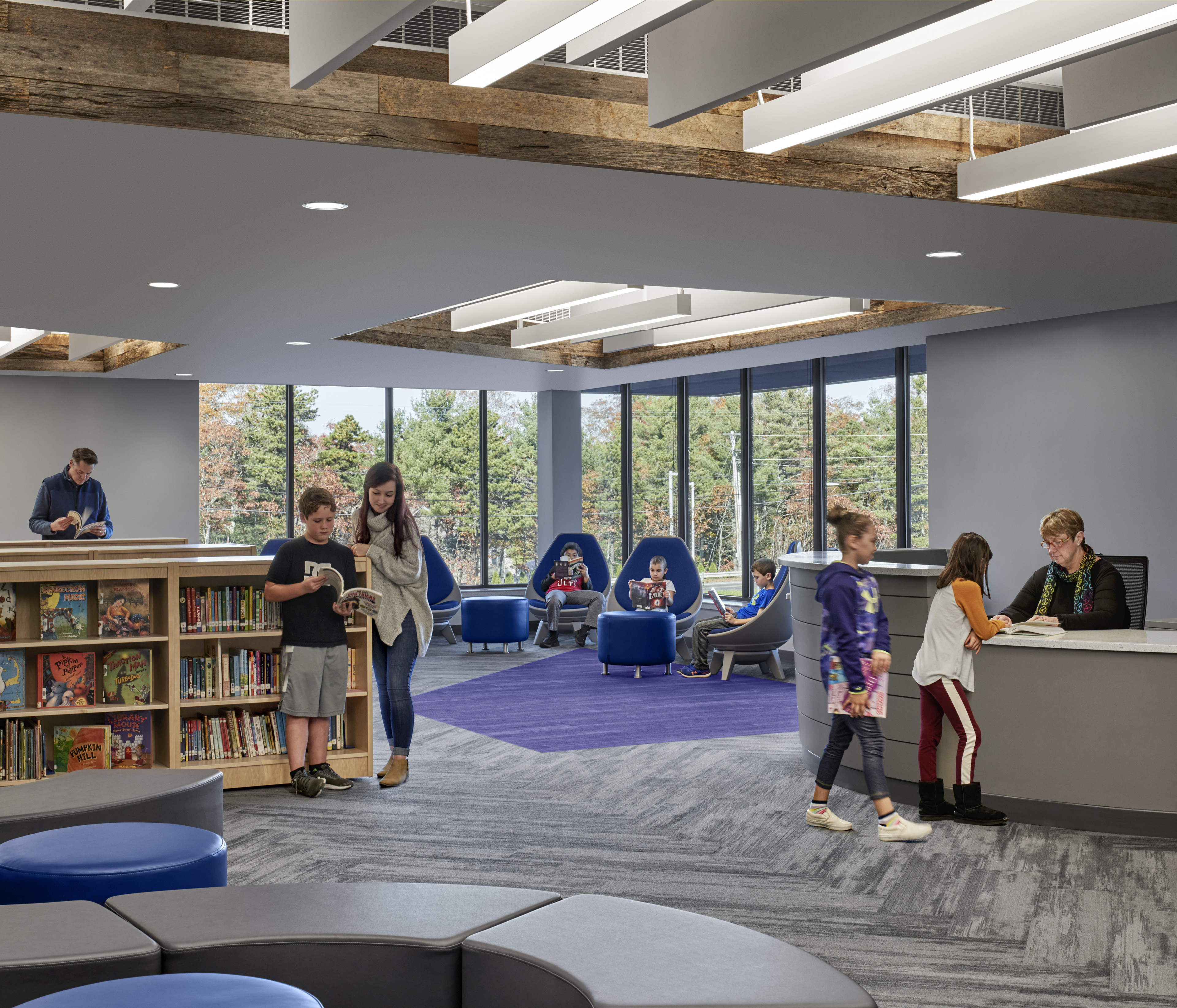 Library with grey carpet, ceiling that opens with light panels, and windows that connect in the corner