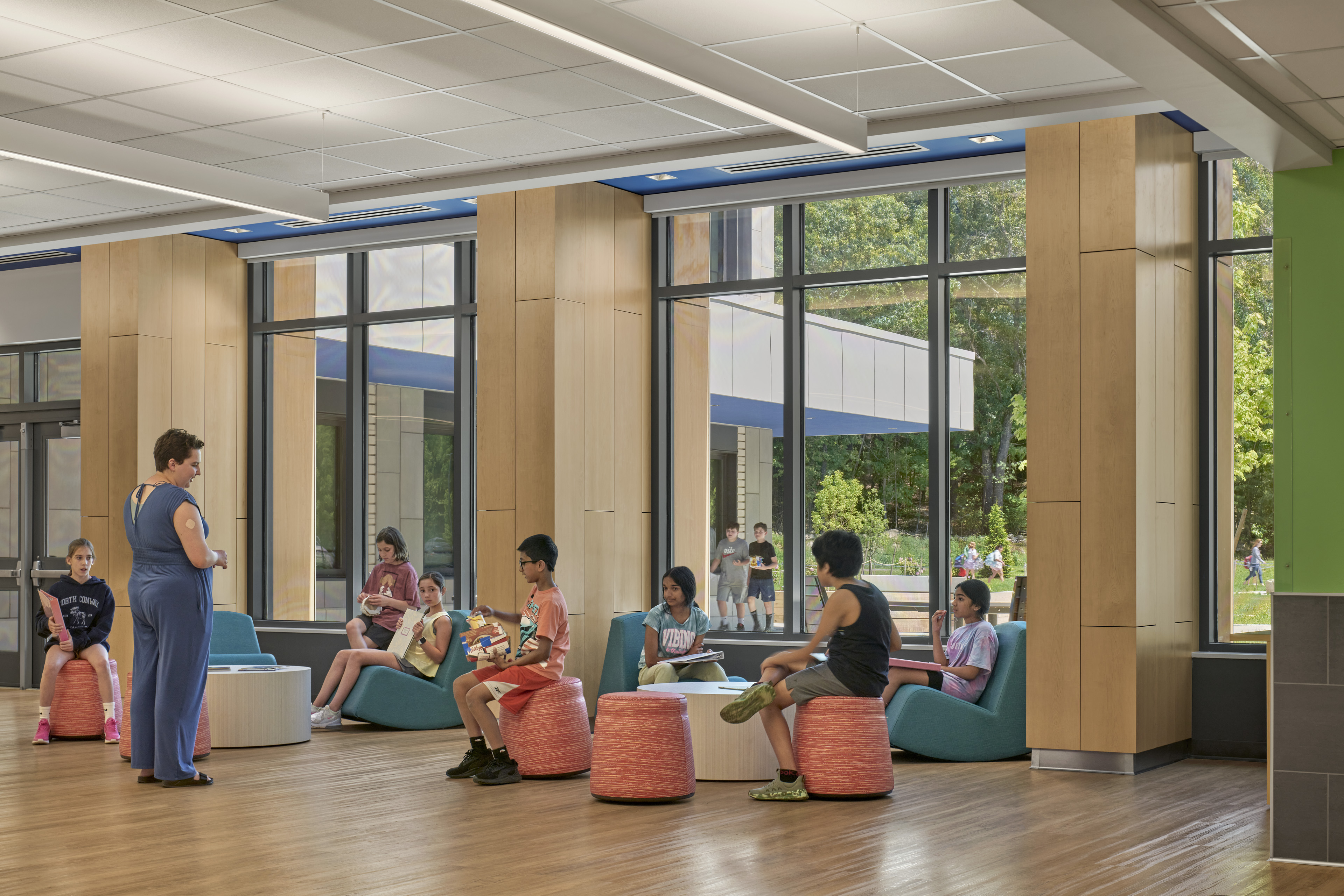 Students hanging out in lounge area seating with windows behind looking out at front lawn