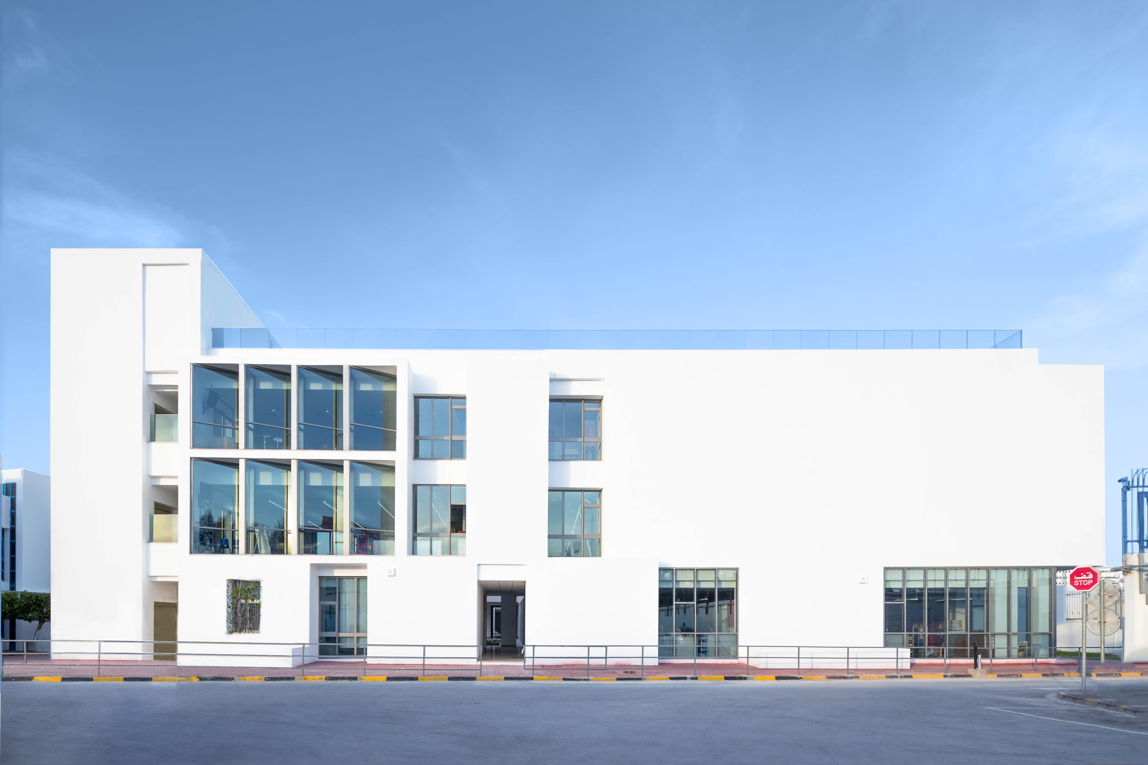 White building with windows on left side, blue sky behind