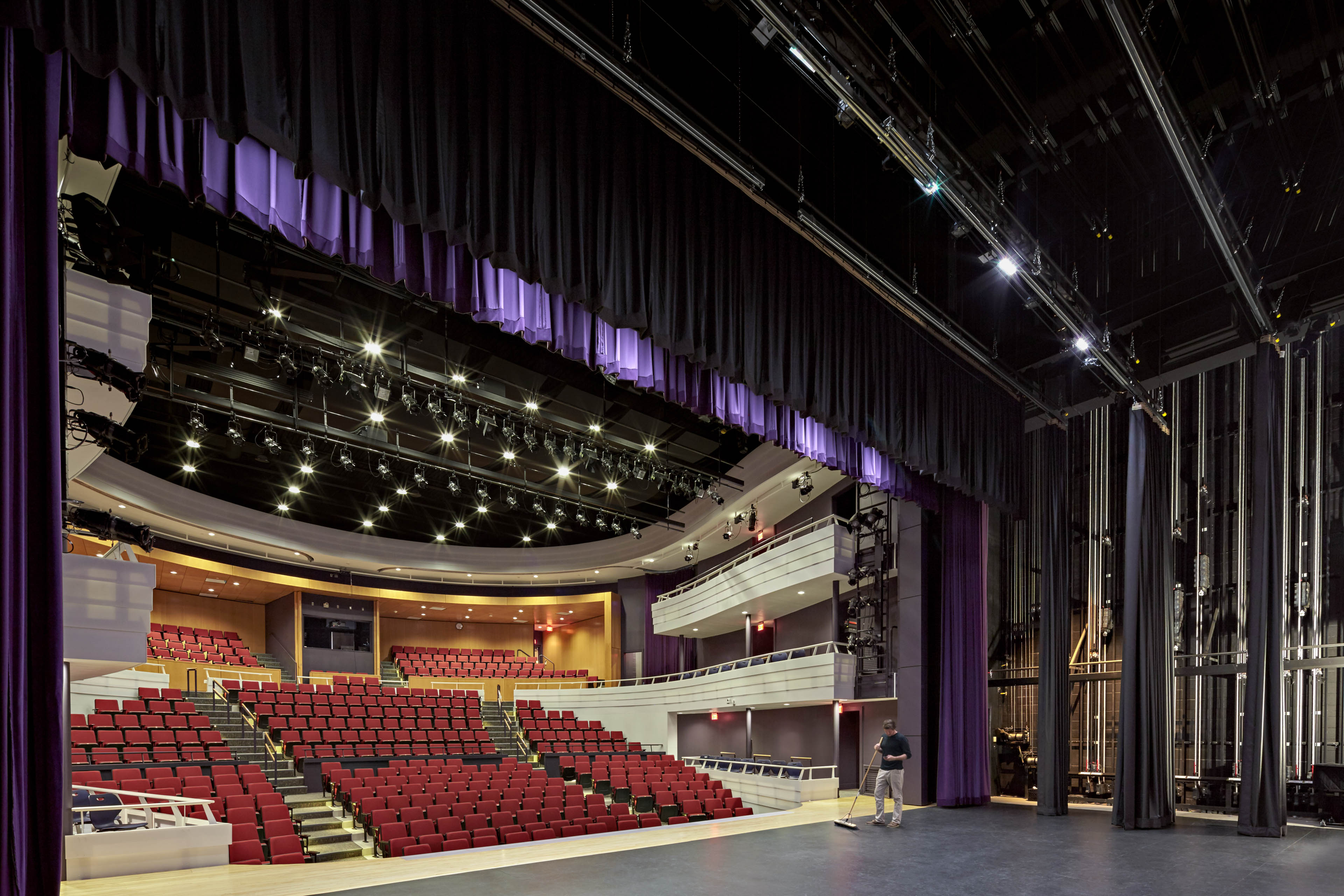 Side angle from left side of stage. Purple curtain and red seats 