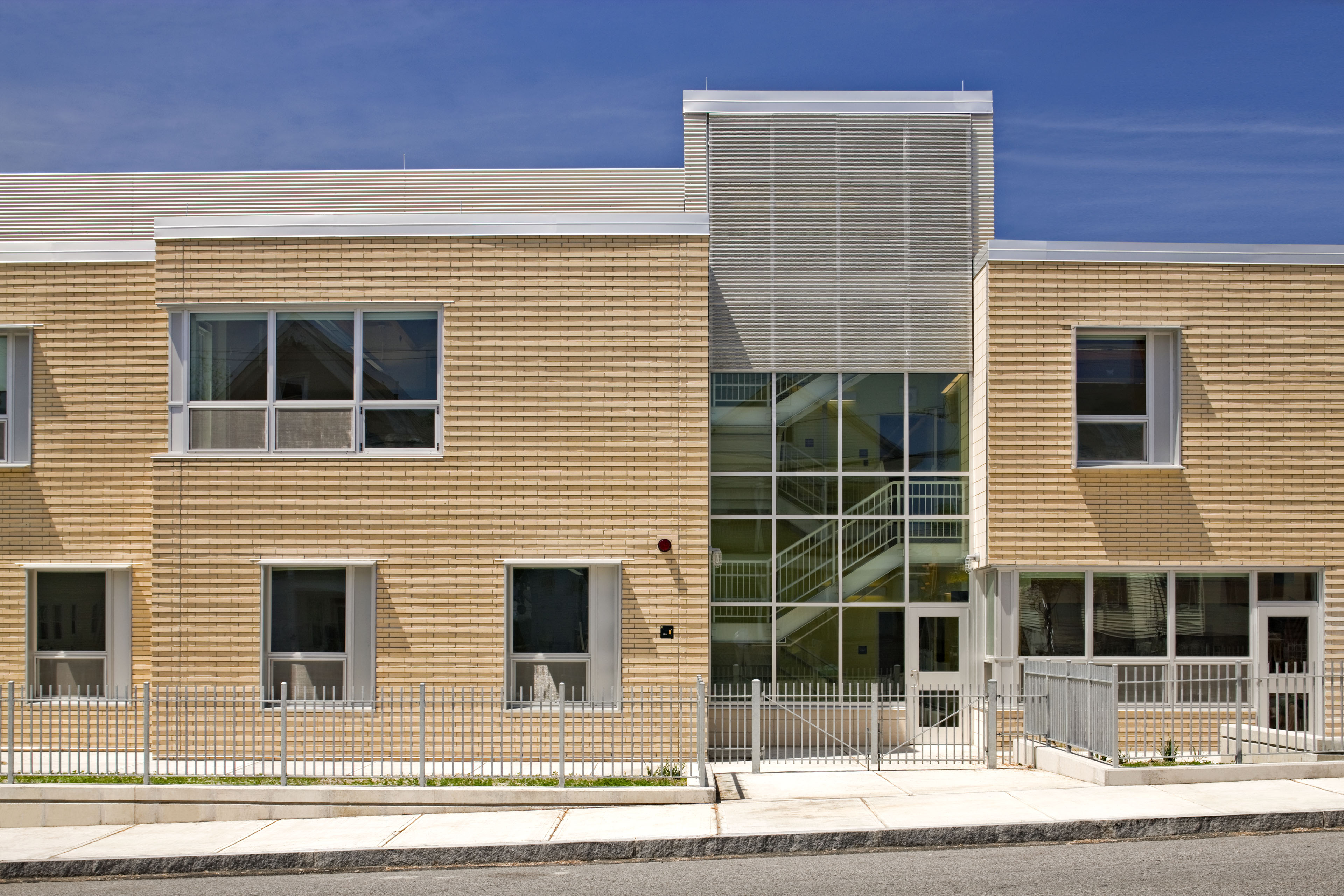 Exterior of school from street view with windows and light colored wood on both buildings