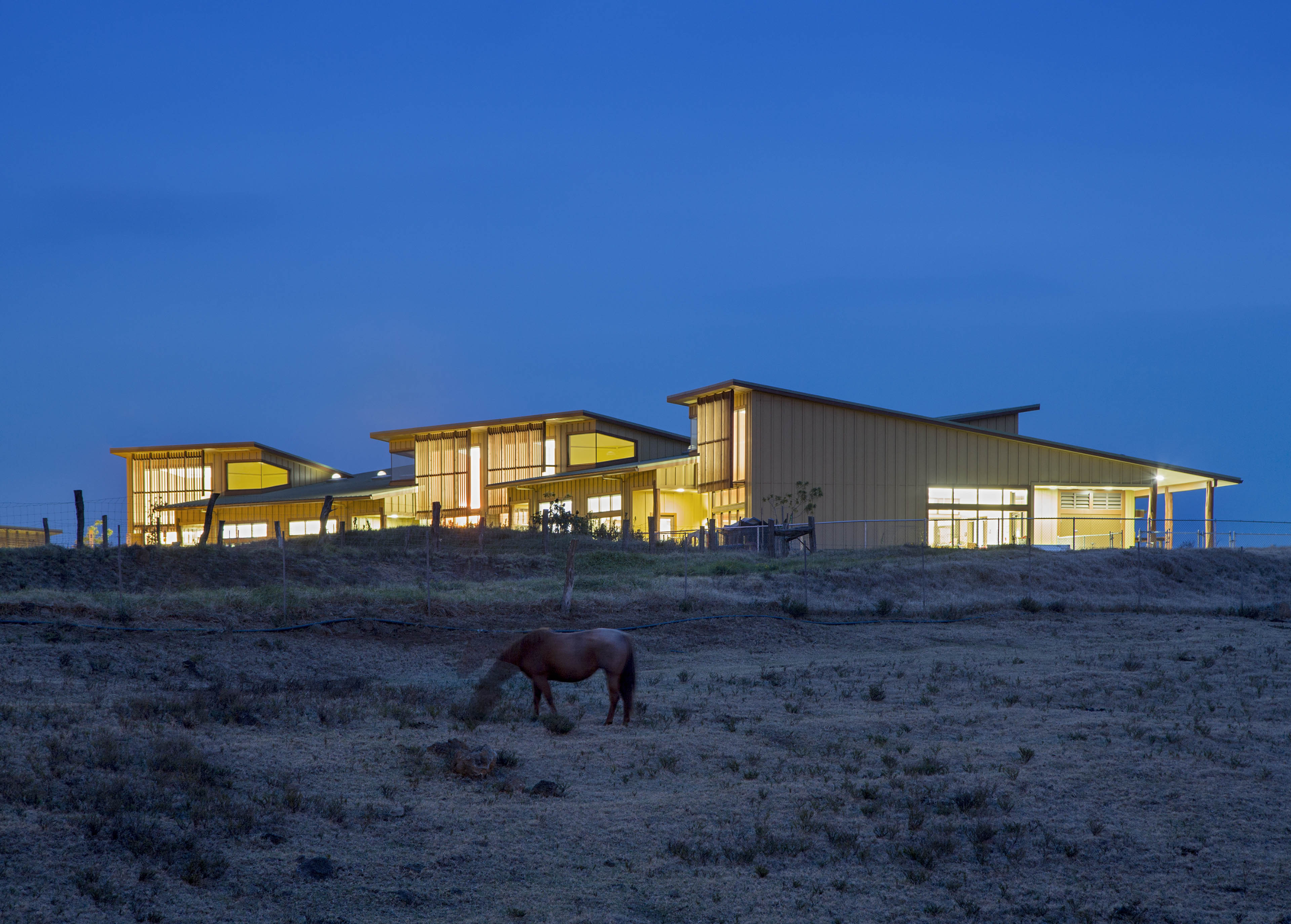 View at night of School from field below with mountains behind and horse grazing in front