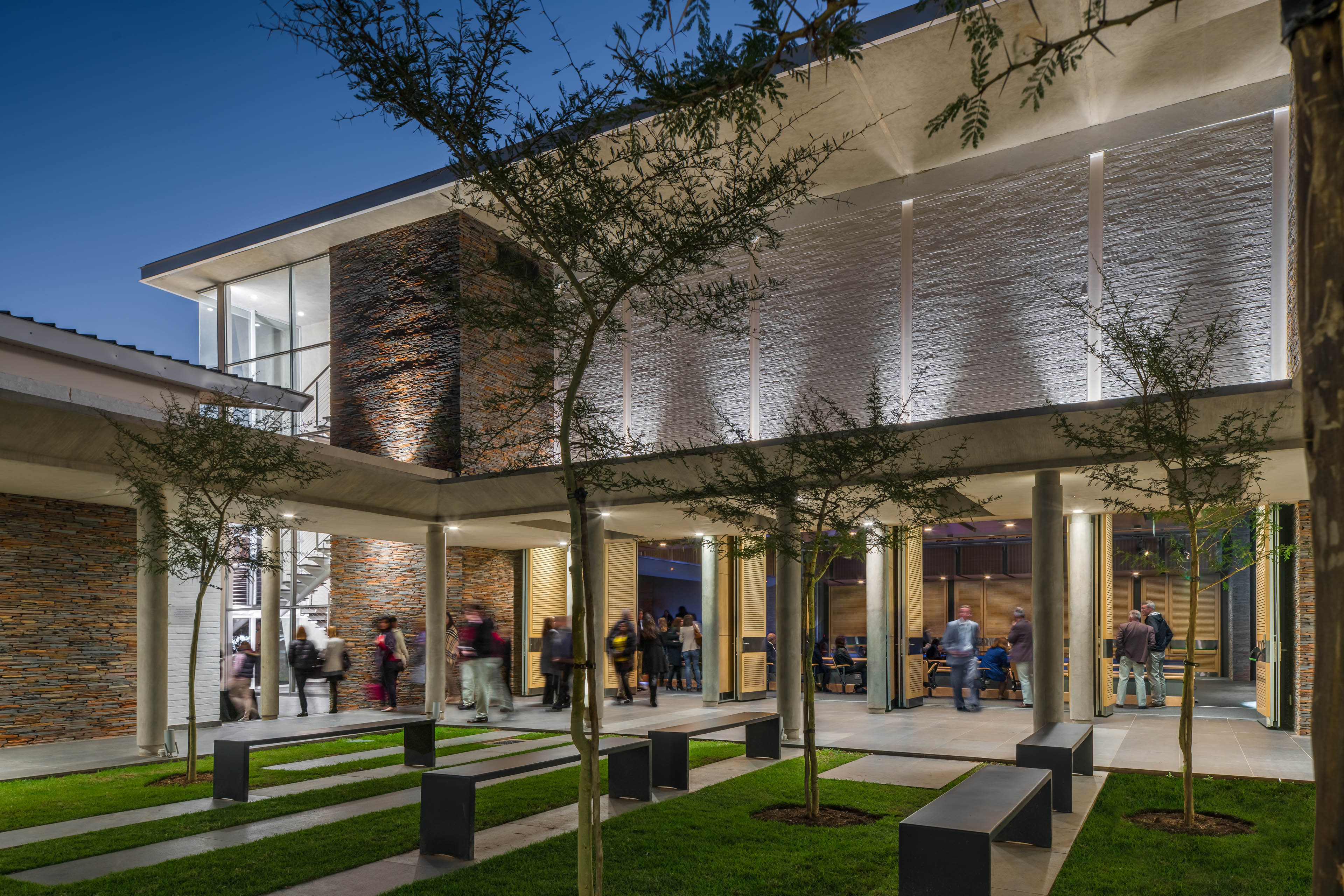 Courtyard at night with patrons passing from theater to additional areas of building 