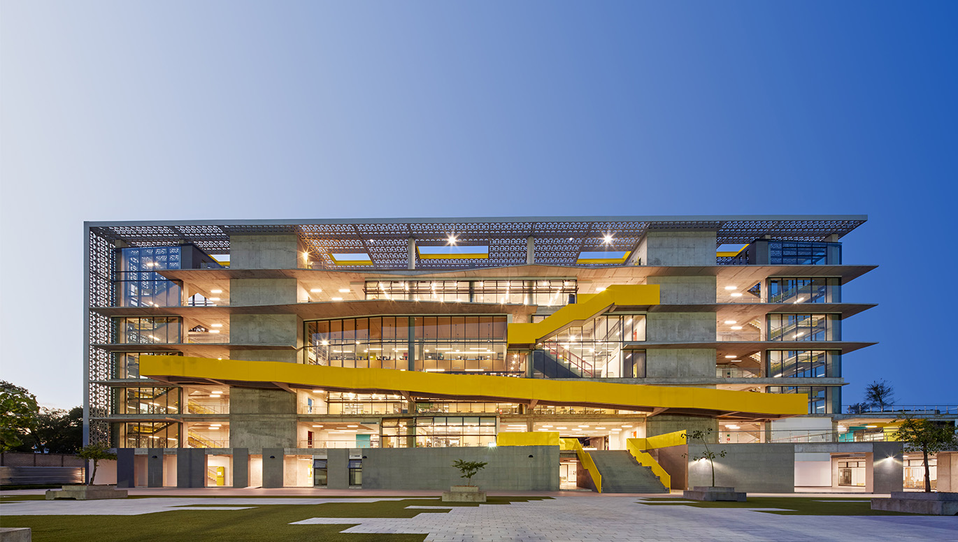 School with seven levels, vertical windows on the left, middle, and right side with beams separating each side and yellow metal strung throughout