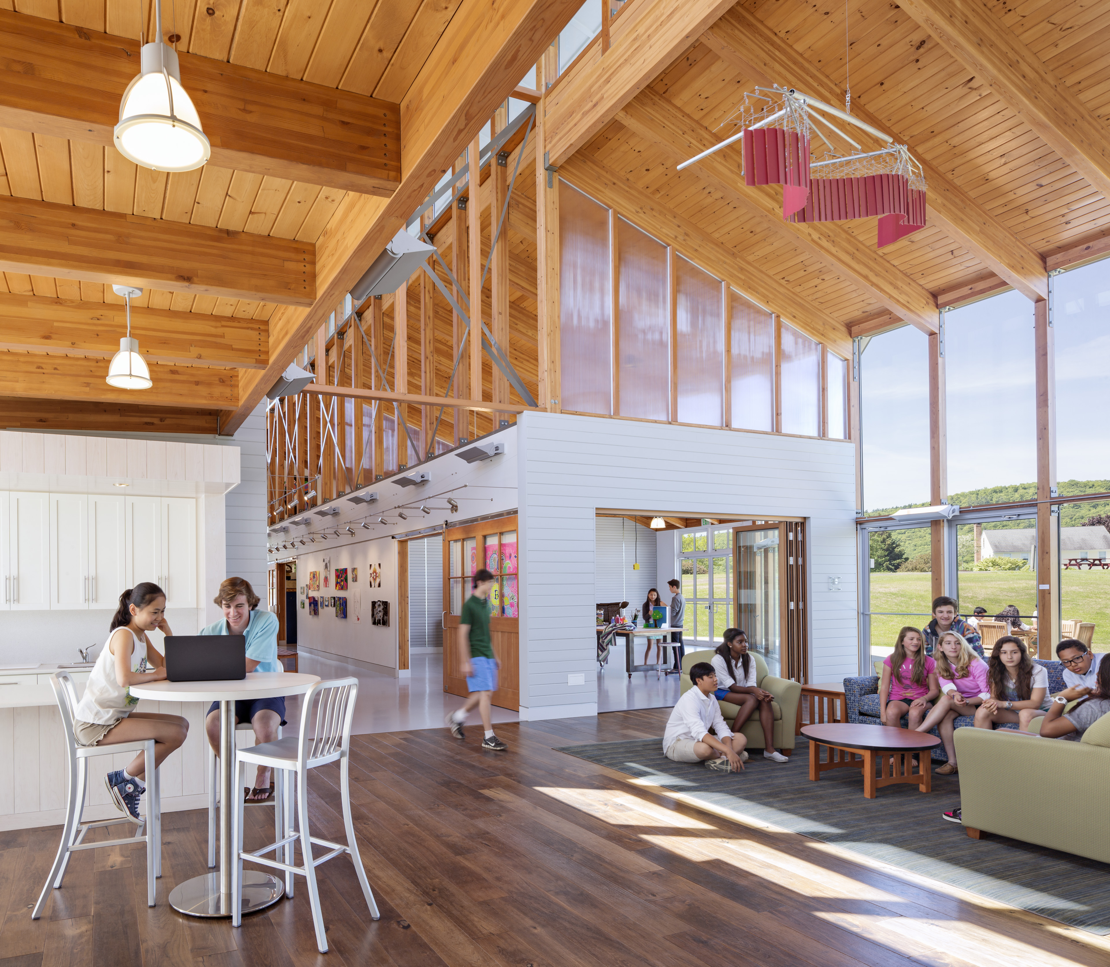Students seated in commons with wood beams on top half of building