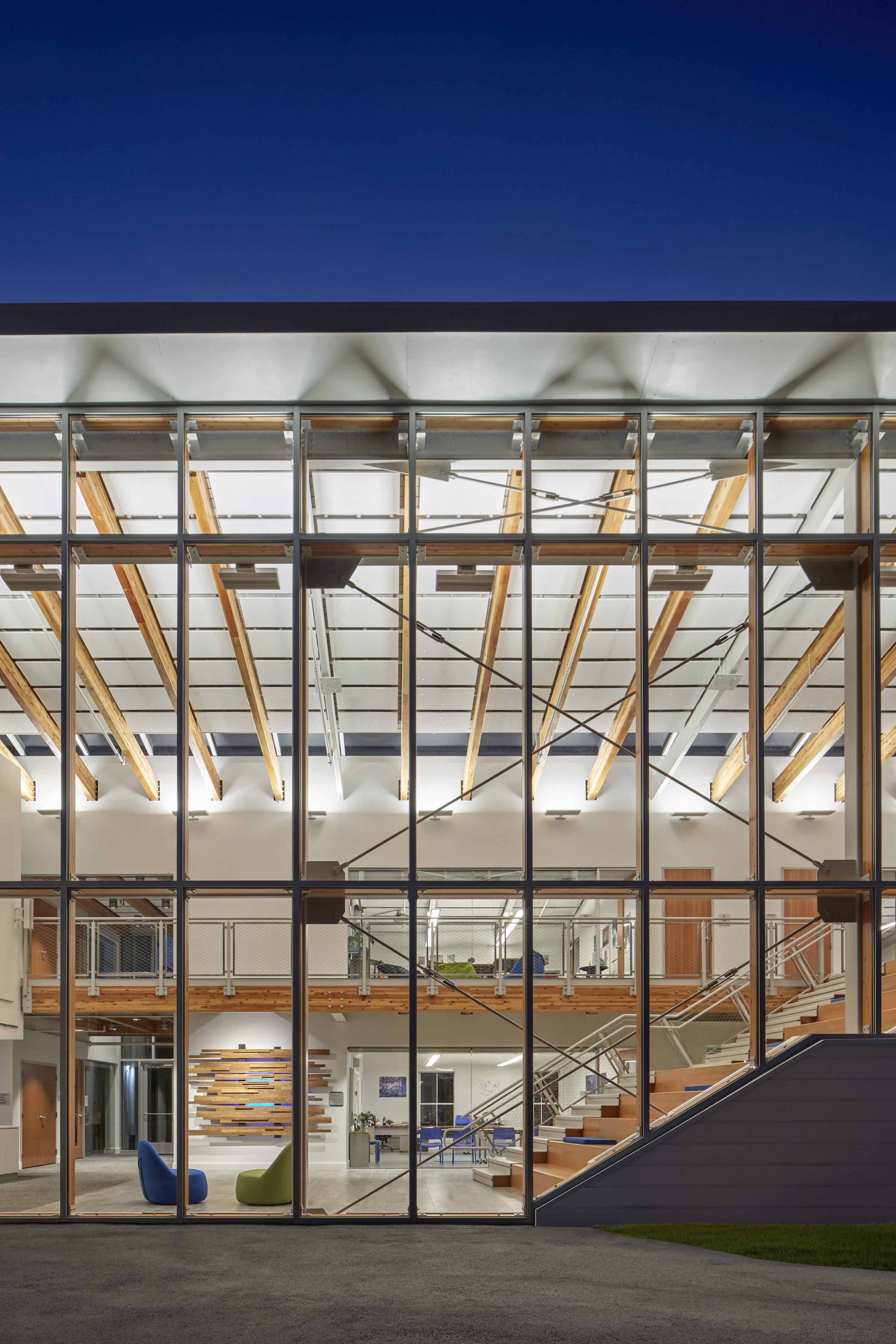 Floor to ceiling windows on the side of building at night with dark blue sky above