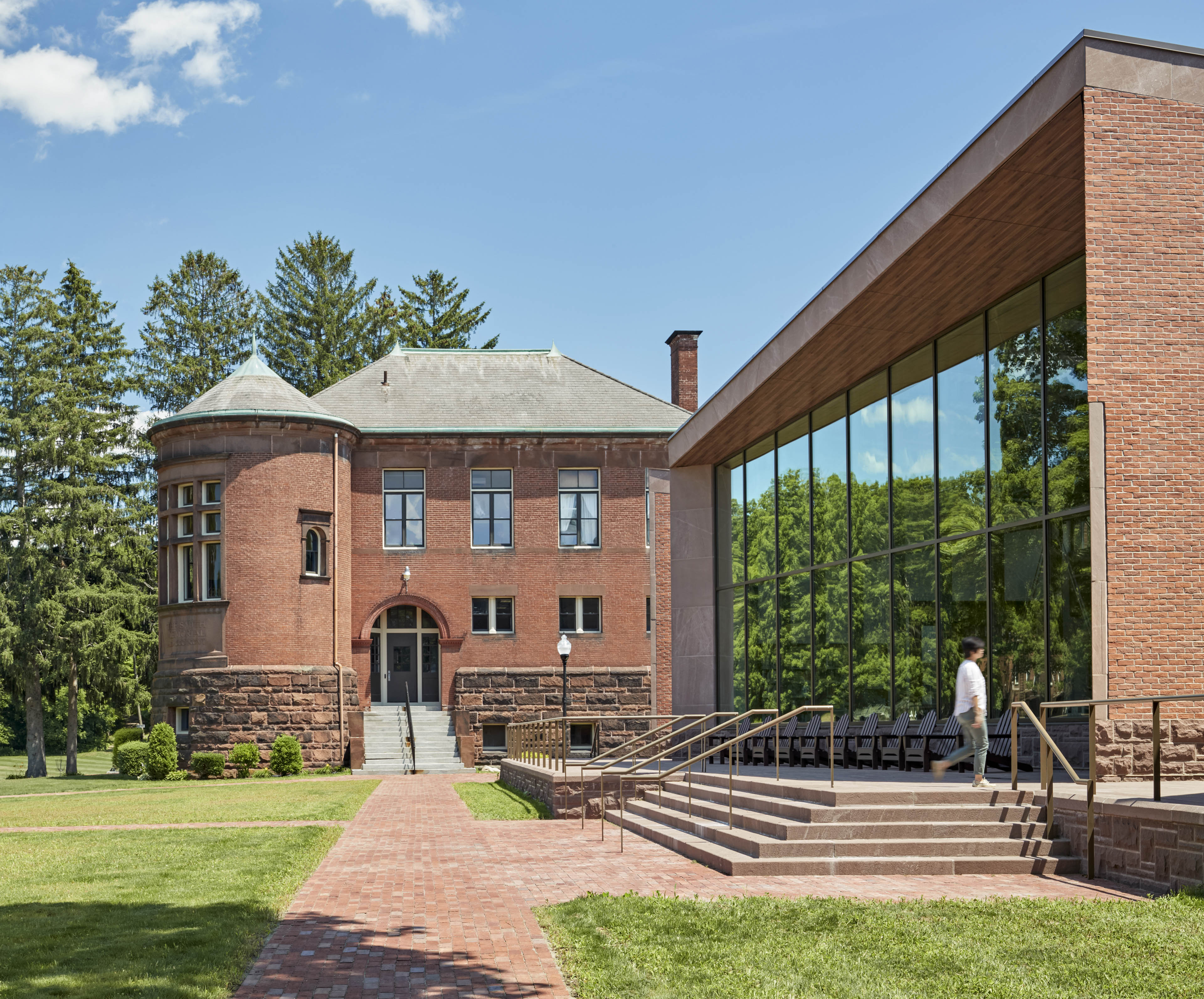 Building in center with walking and entrance to the right with large vertical windows and stairs leading up