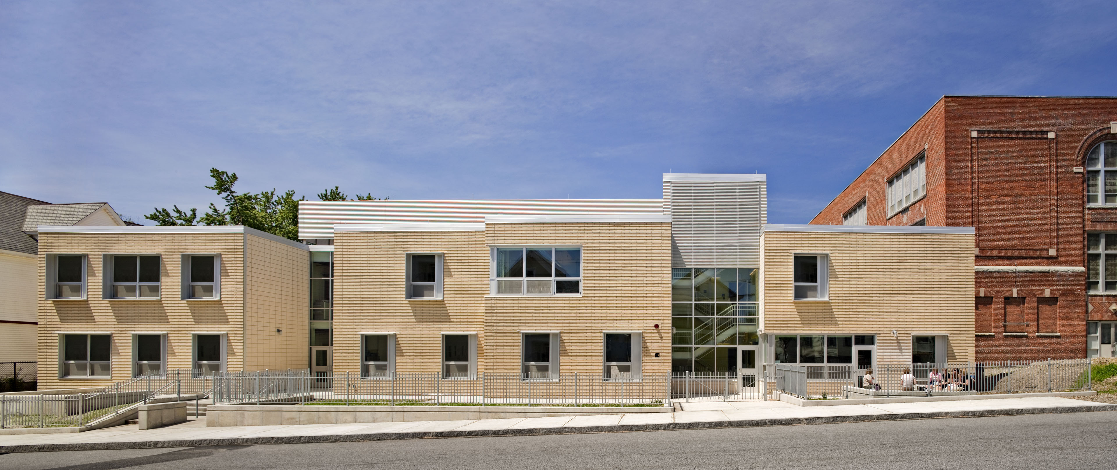 Exterior of school from street view with windows and light colored wood on both buildings