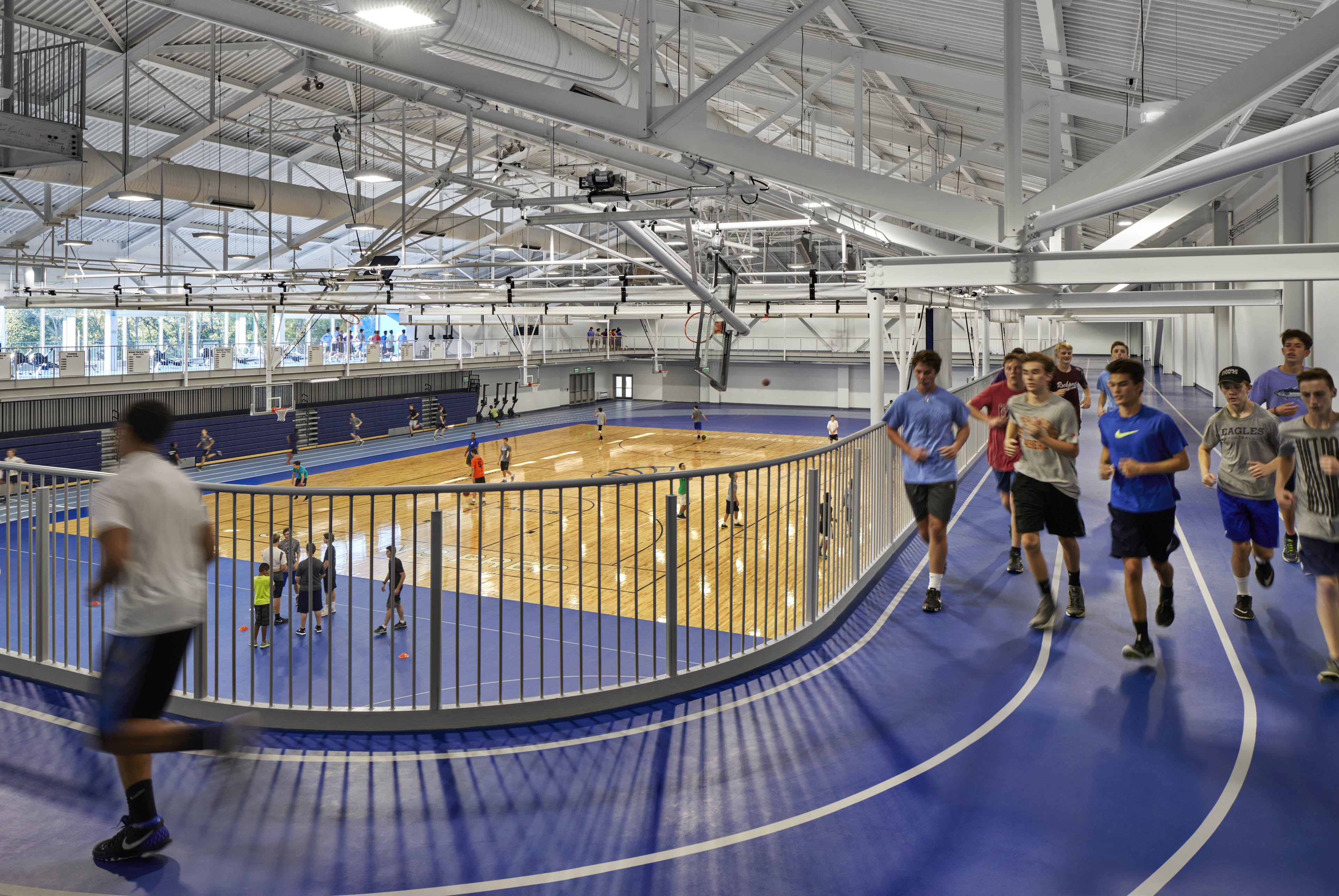 Students running around track on second floor of gymnasium, and students using basketball court on first floor