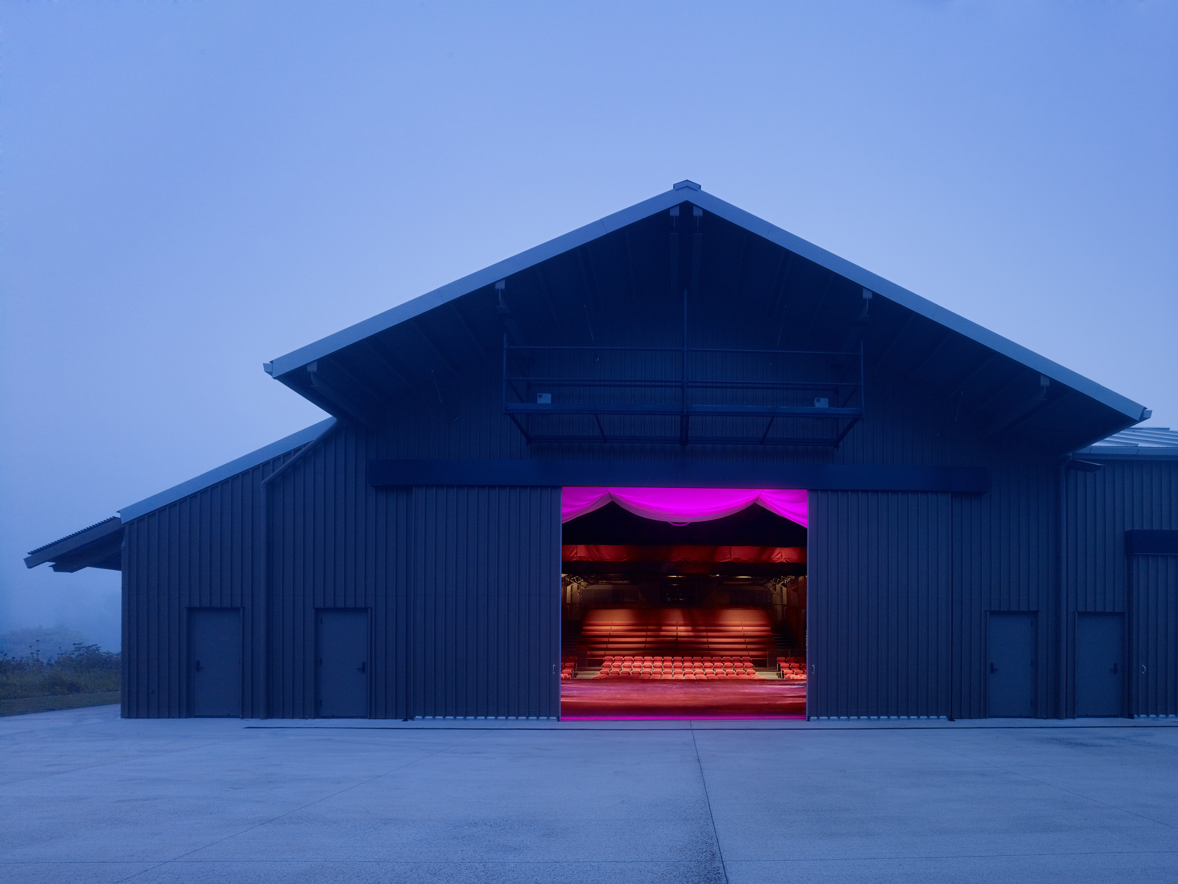 Exterior of theater on a misty night with neon pink and red light displayed from entrance
