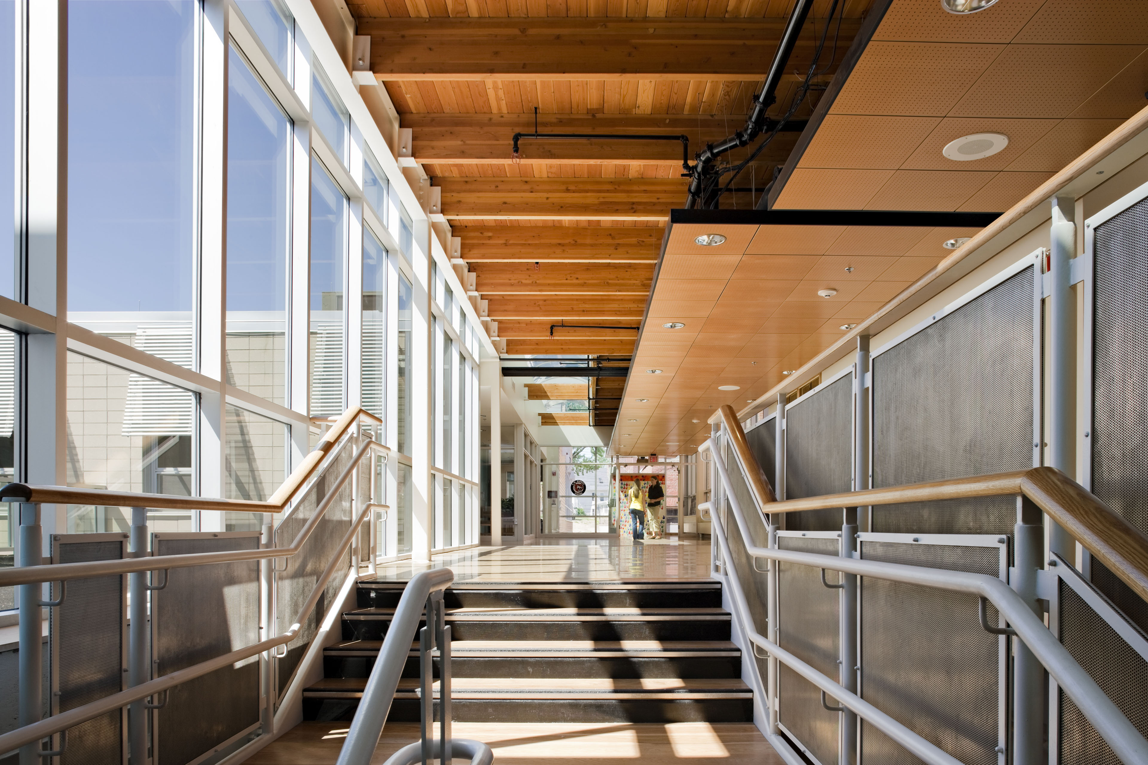 Interior corridor with steps leading up and bright light from windows on left side filter in