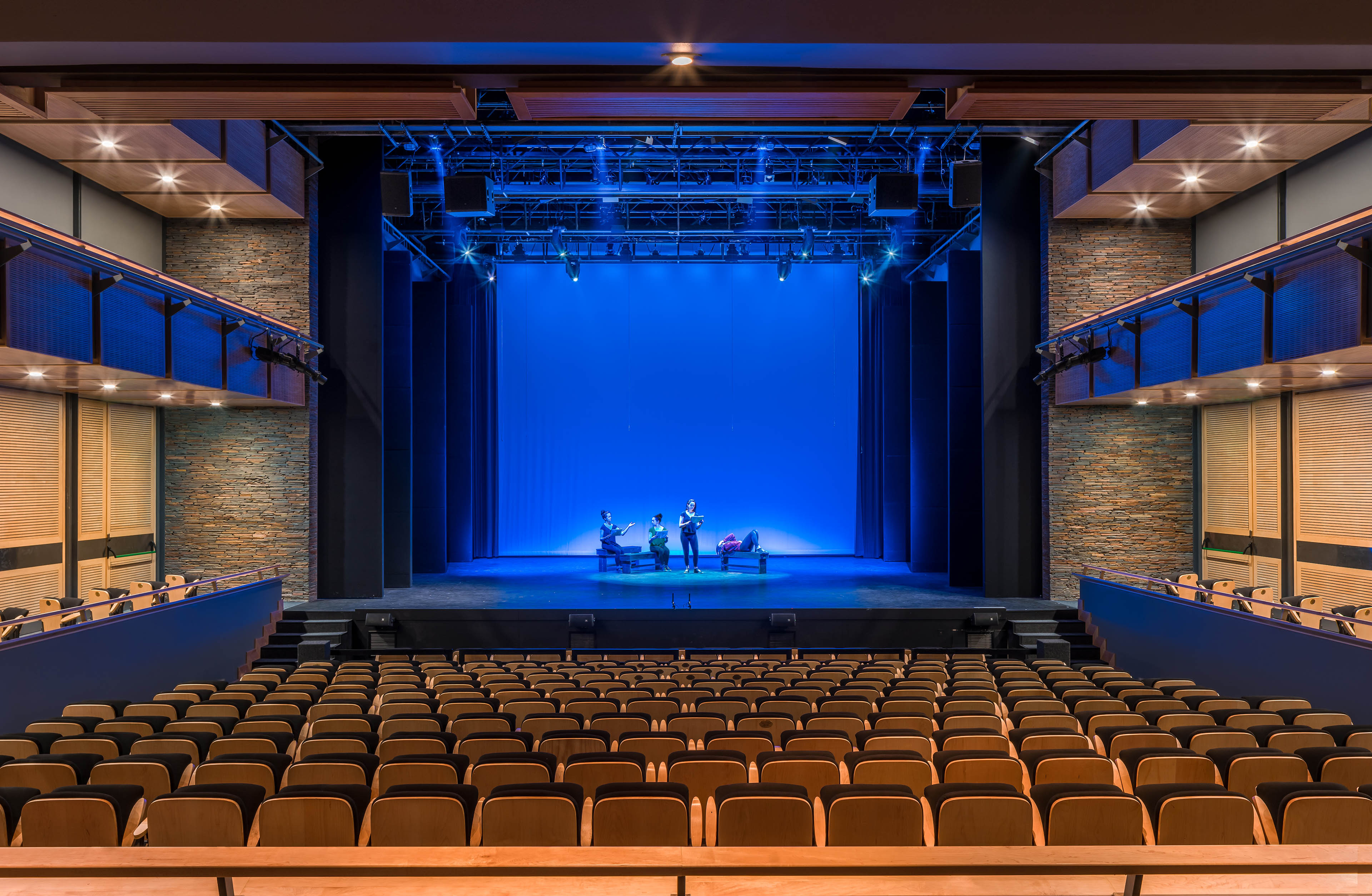View from balcony of theater, with blue stage lights and thespians performing