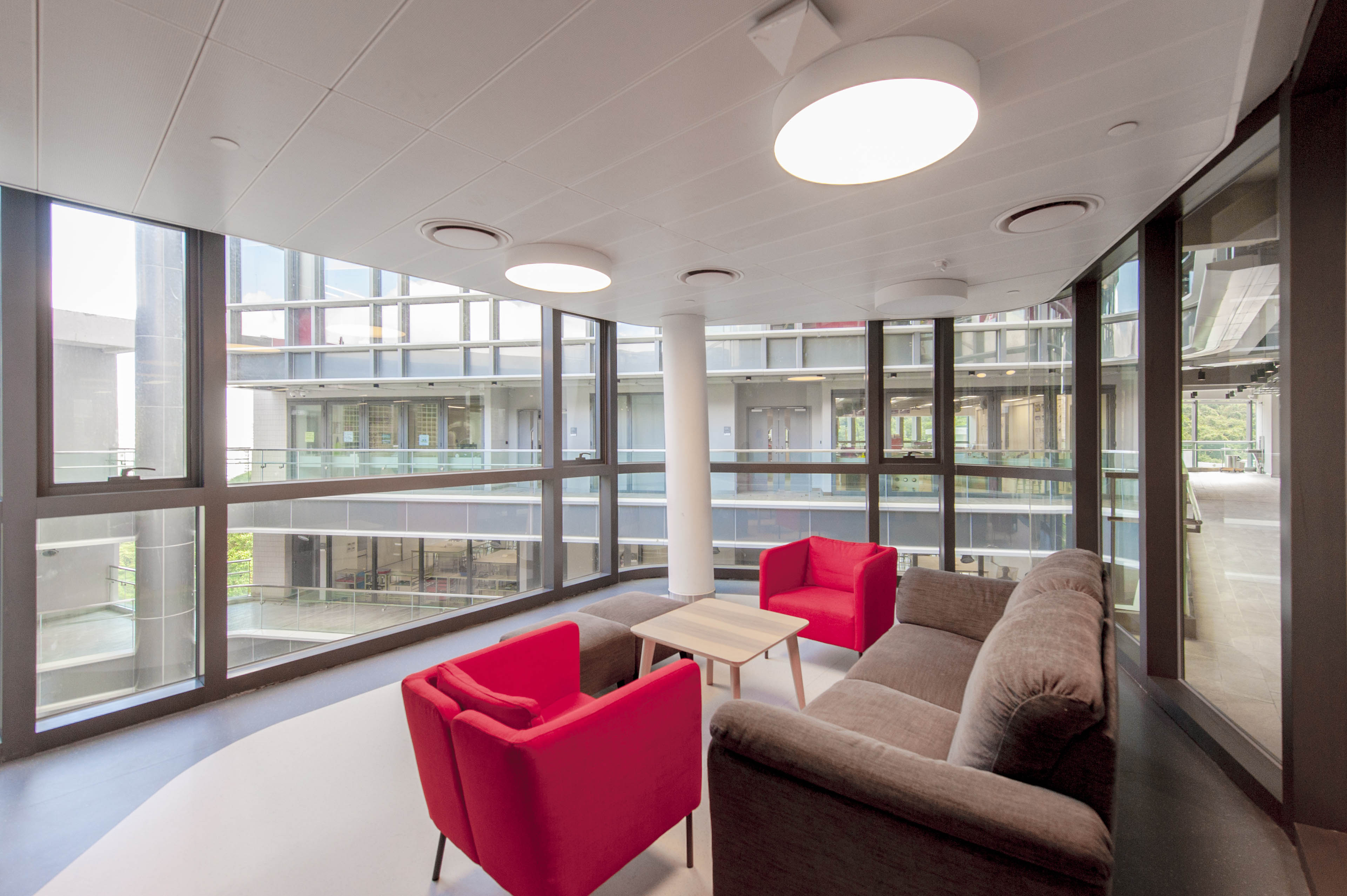 Interior red lounge chairs and sofa with windows surrounding 