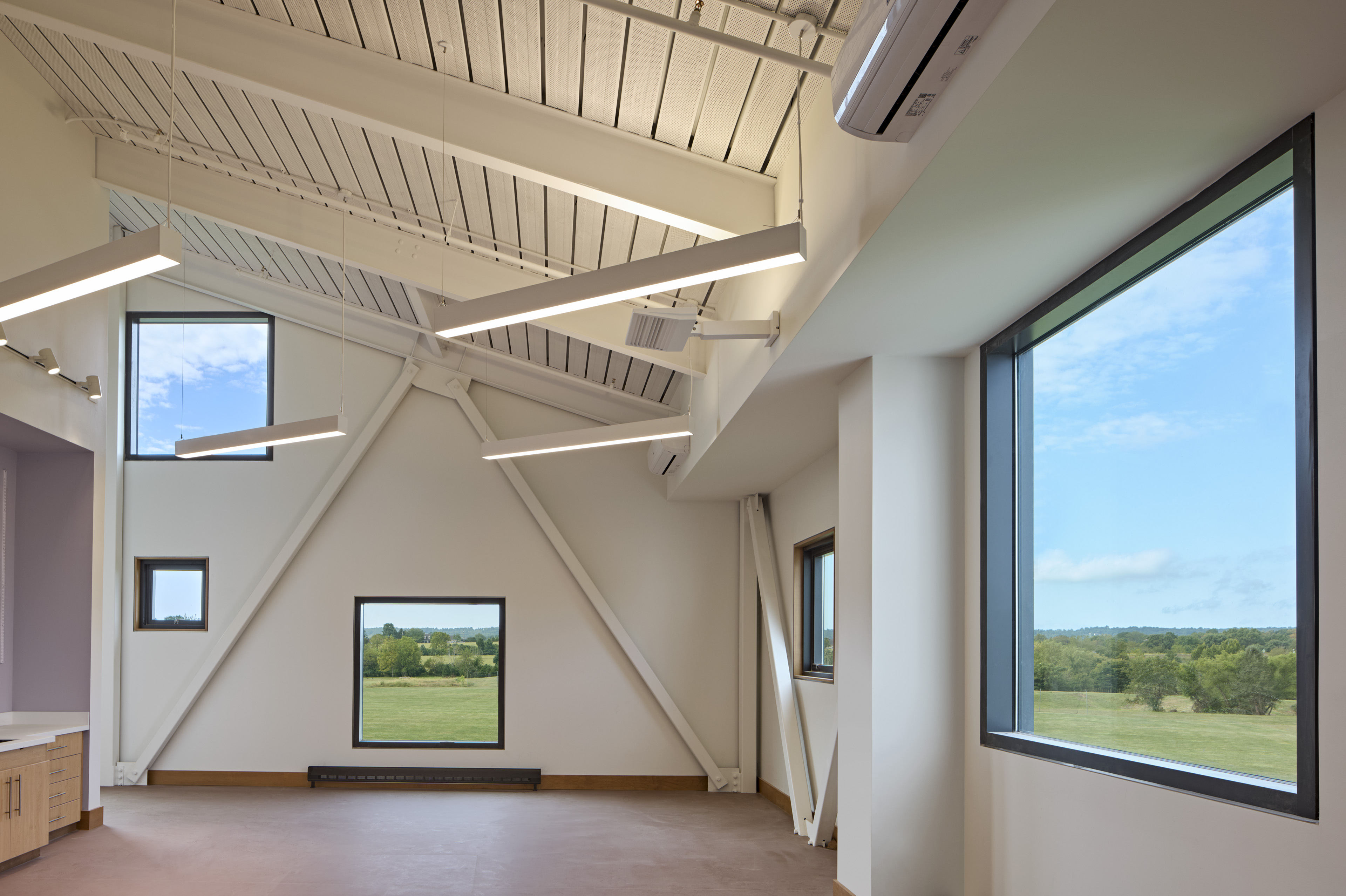 Interior room with triangle on formation on wall and large window to the right overlooking fields