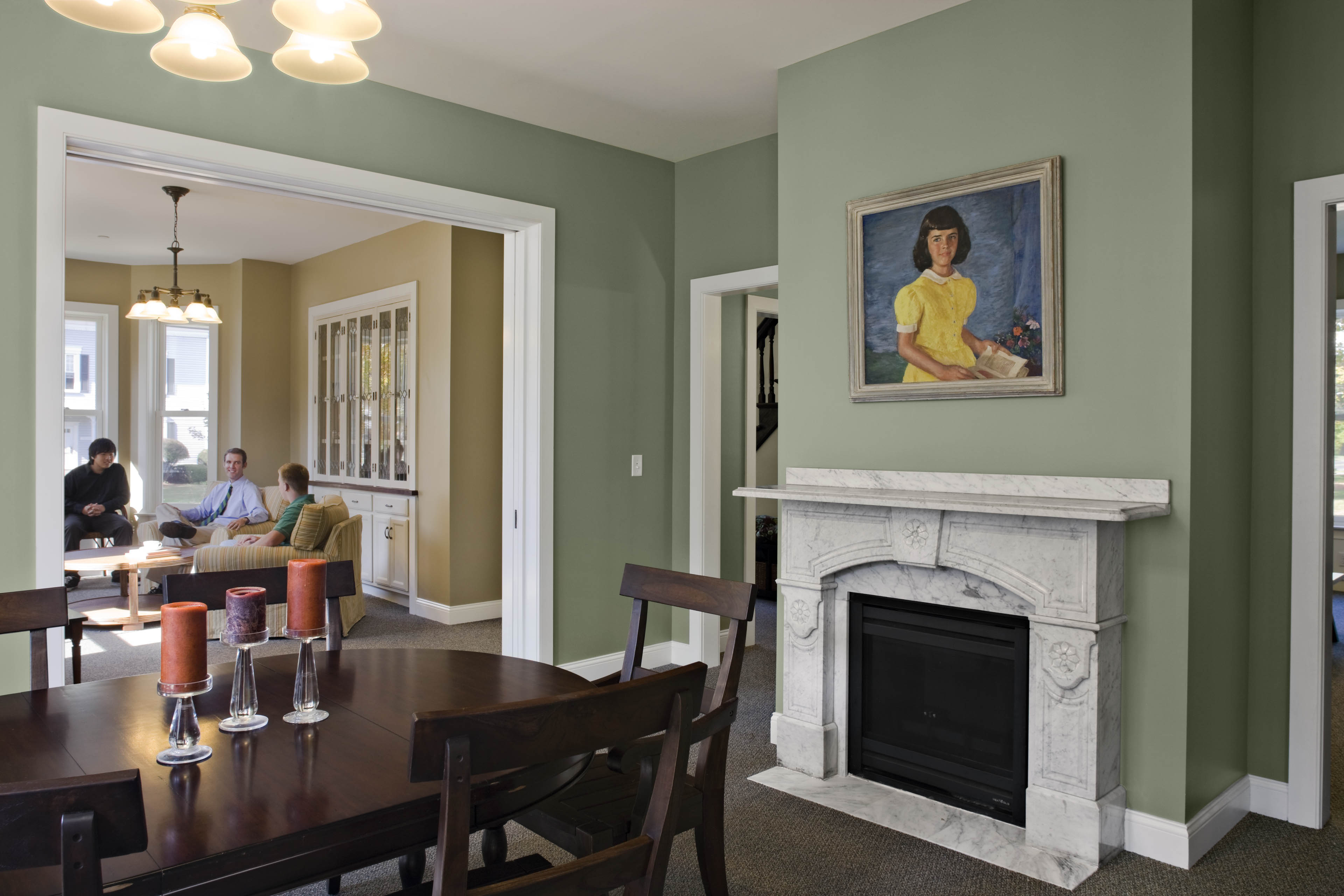 Interior lounge area of dorm, with sage green walls, fire place and a dining room table