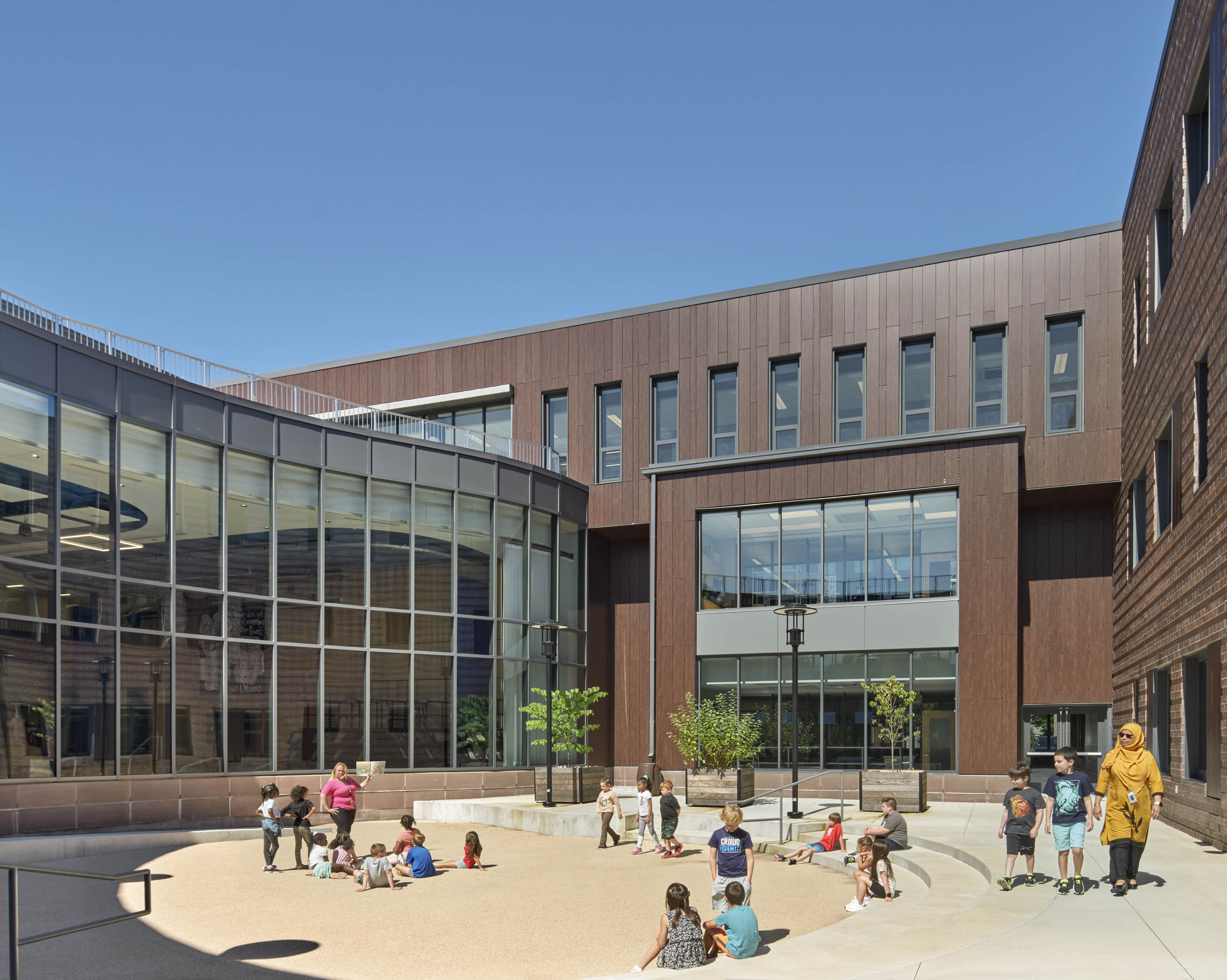 Students sat at interior courtyard with staggered open play area and building behind and to the side