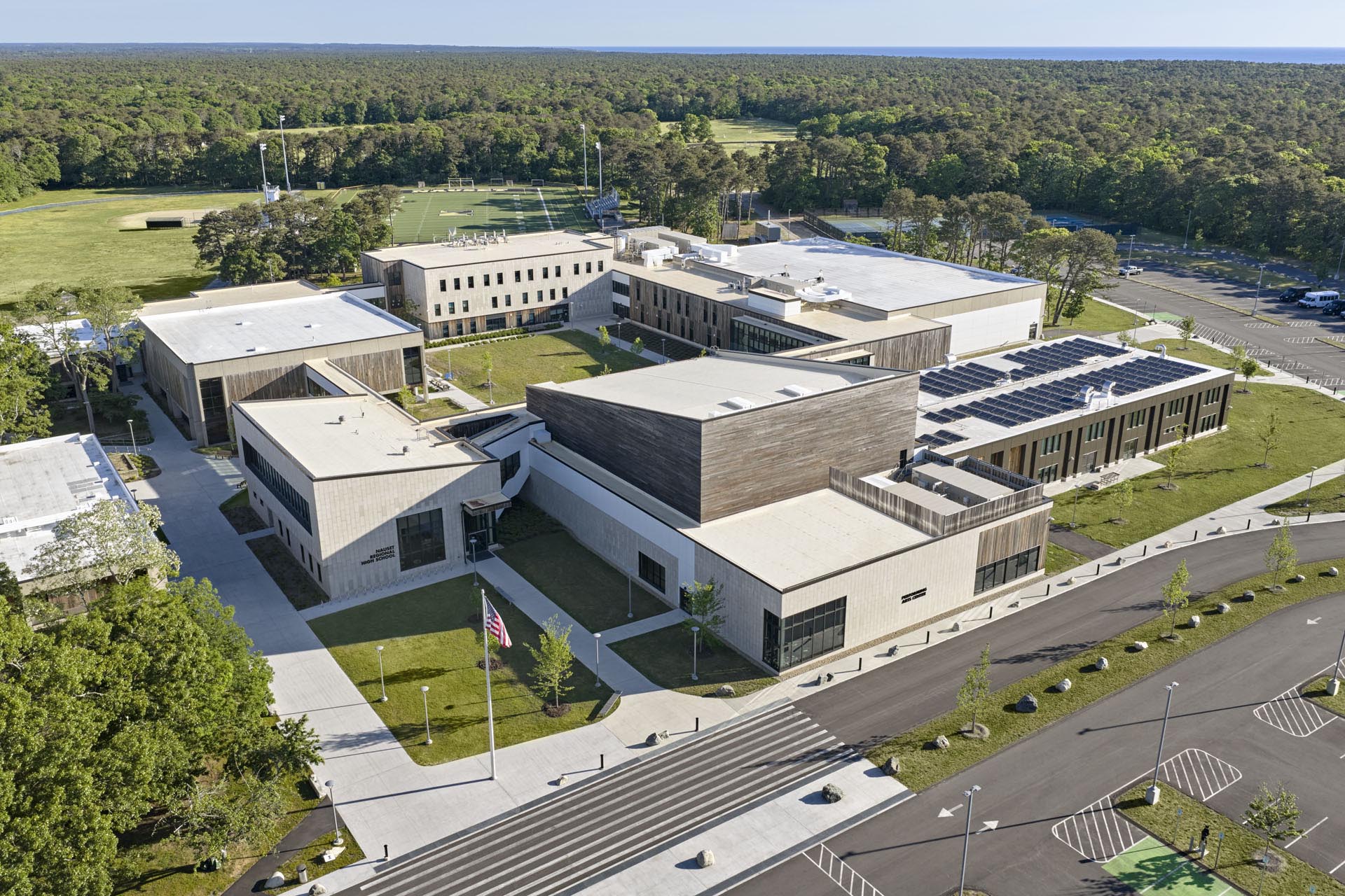 Aerial view of site with drop off lane in front and grass and trees to the side and behind