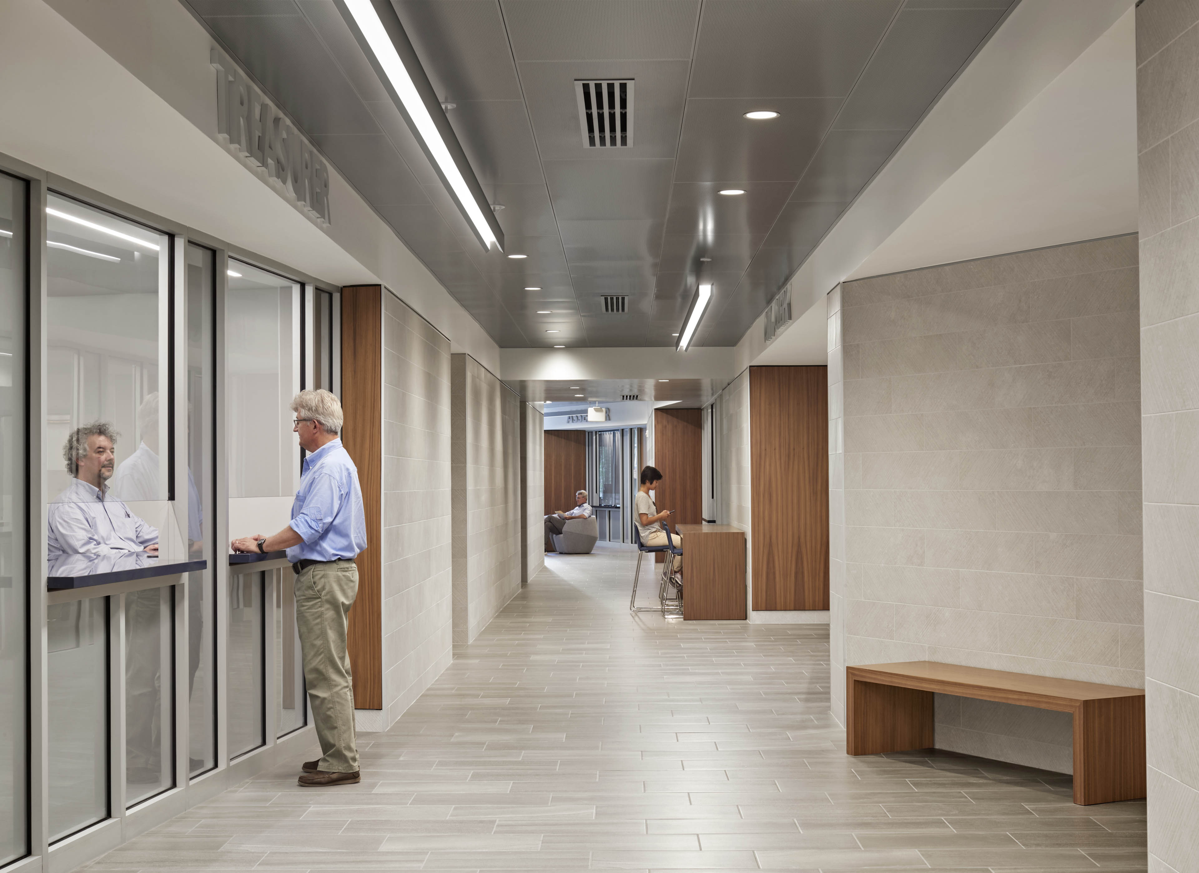 Interior corridor with walk-up window in use, benches along the side and additional seating in back
