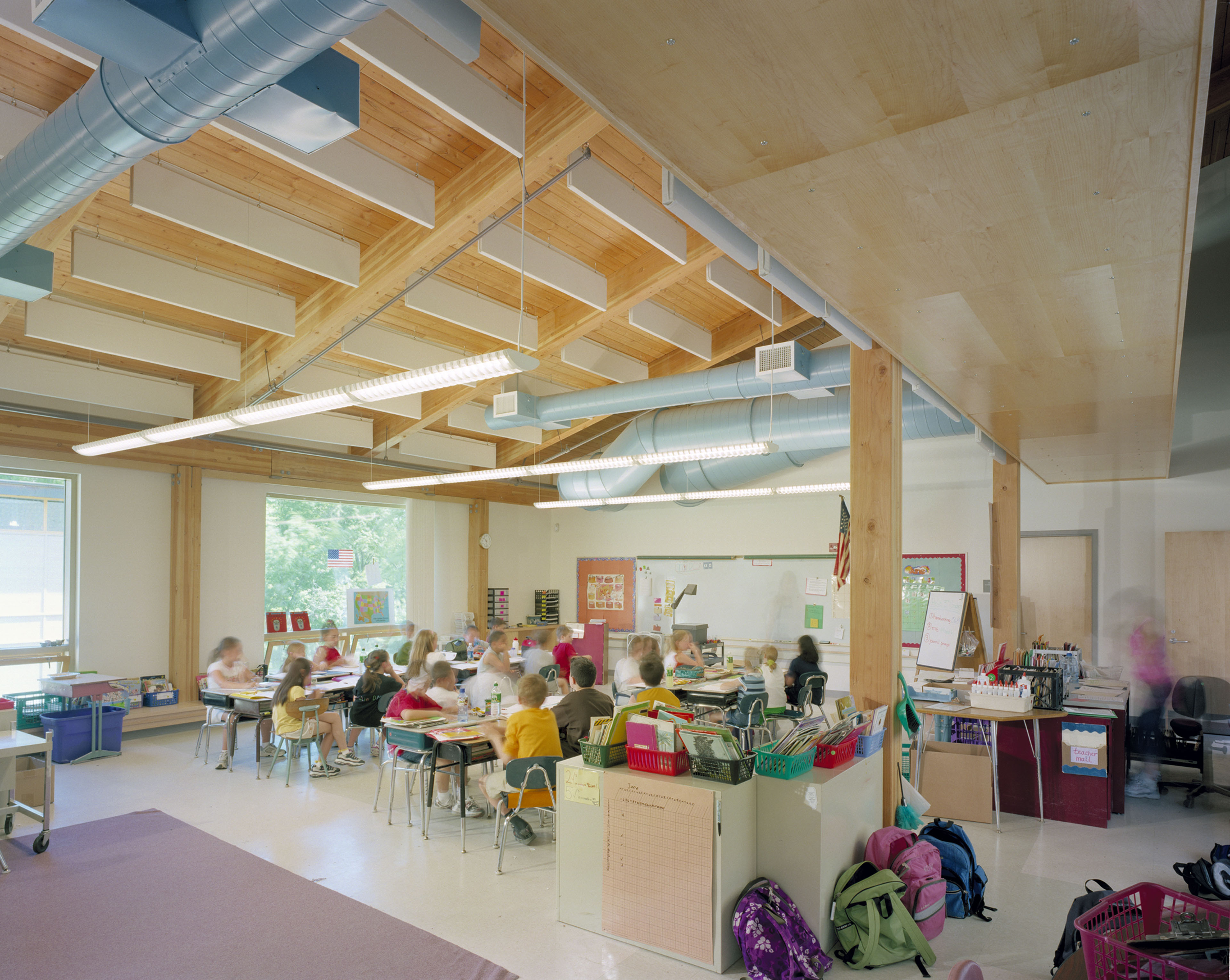 Students seated in classroom with wood beams and wood paneling on ceiling 