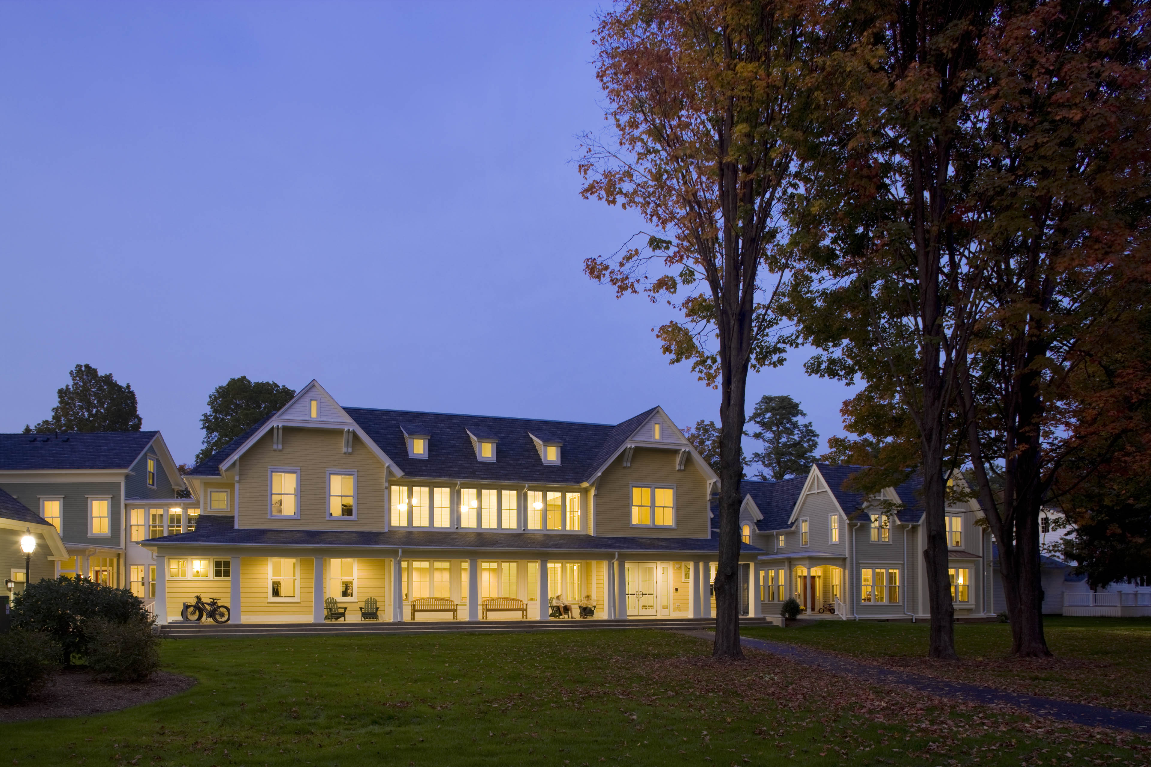 Building at night with yellow light radiating out, trees to the right and dark blue sky behind