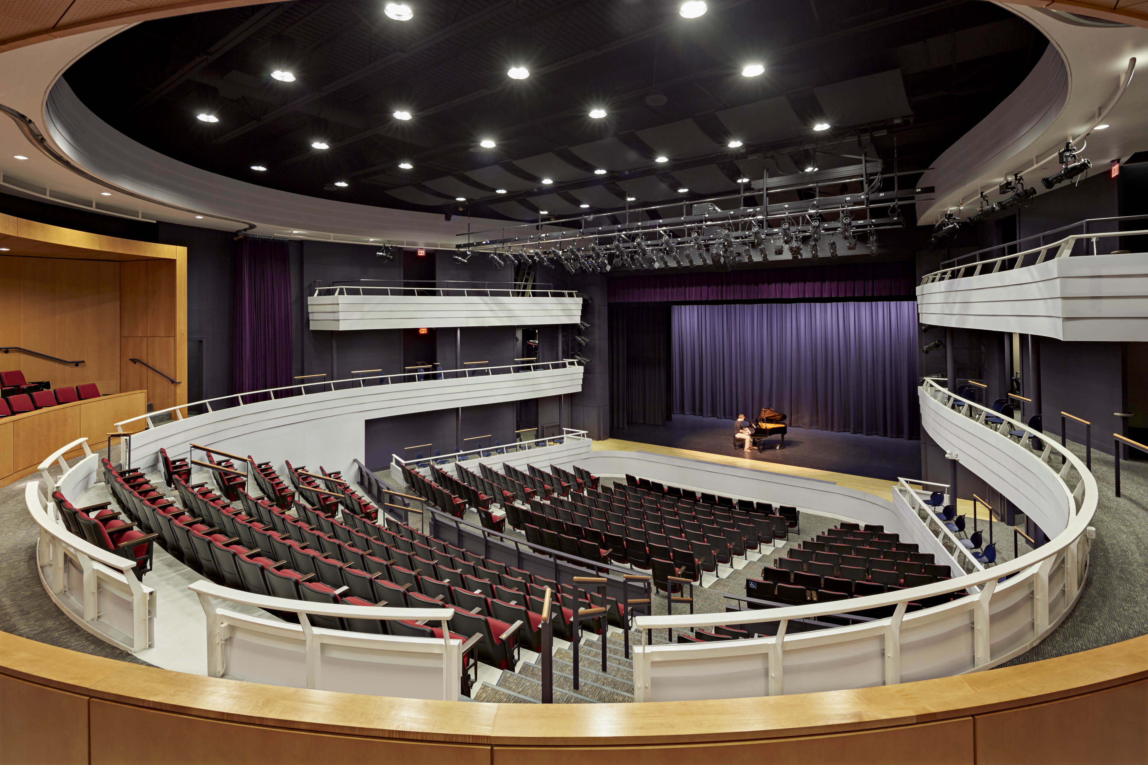 Side angle from back of theater. Purple curtain and red seats 