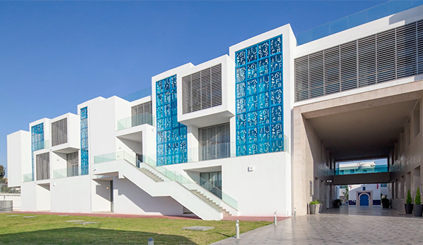 Side angle of white building with light blue windows and green grass in front
