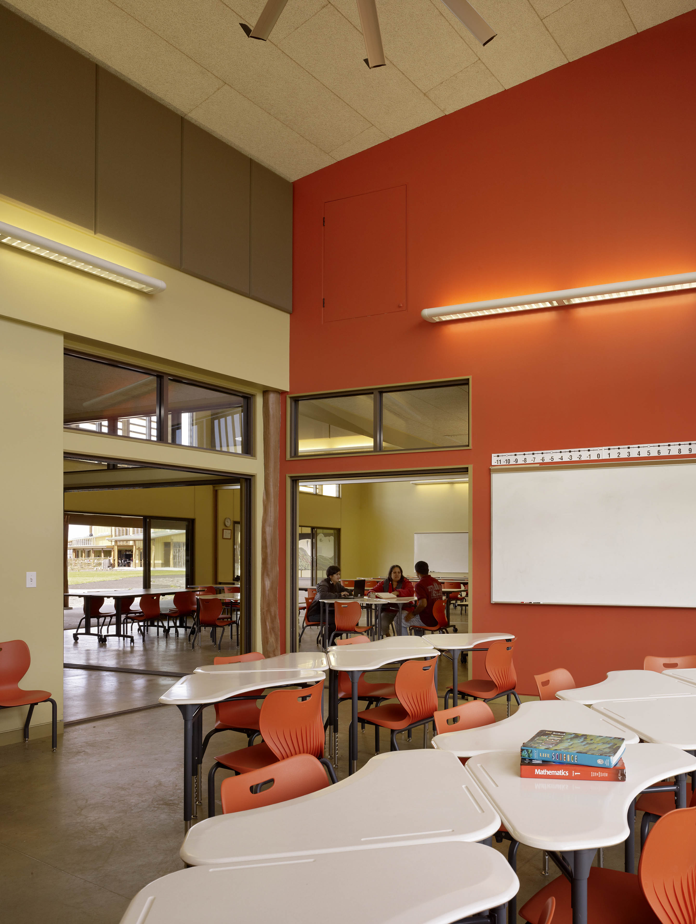 Classroom with red wall to the right and modular desks clustered together 