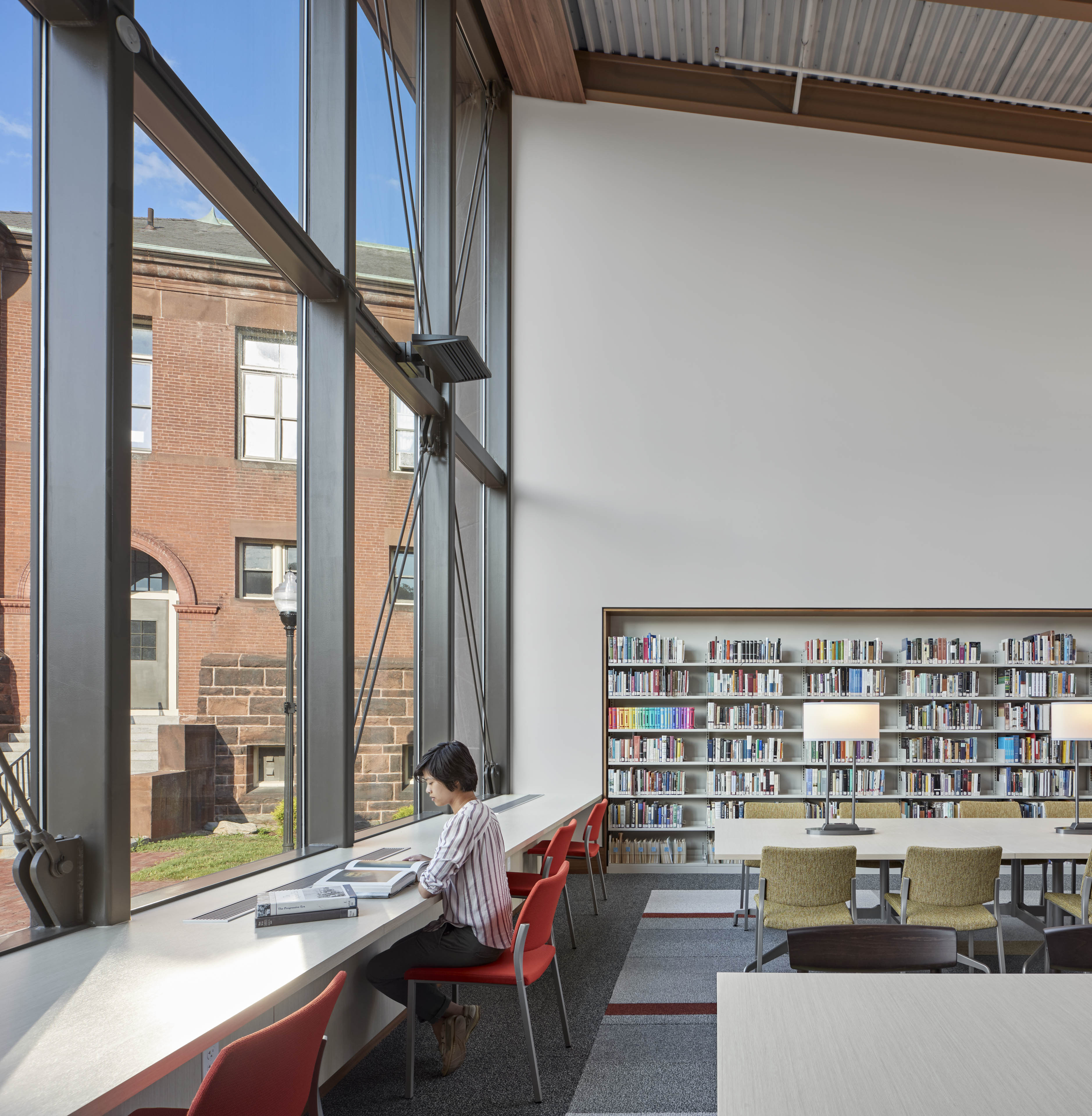 Library with windows to the left looking out on courtyard and book shelves on back wall