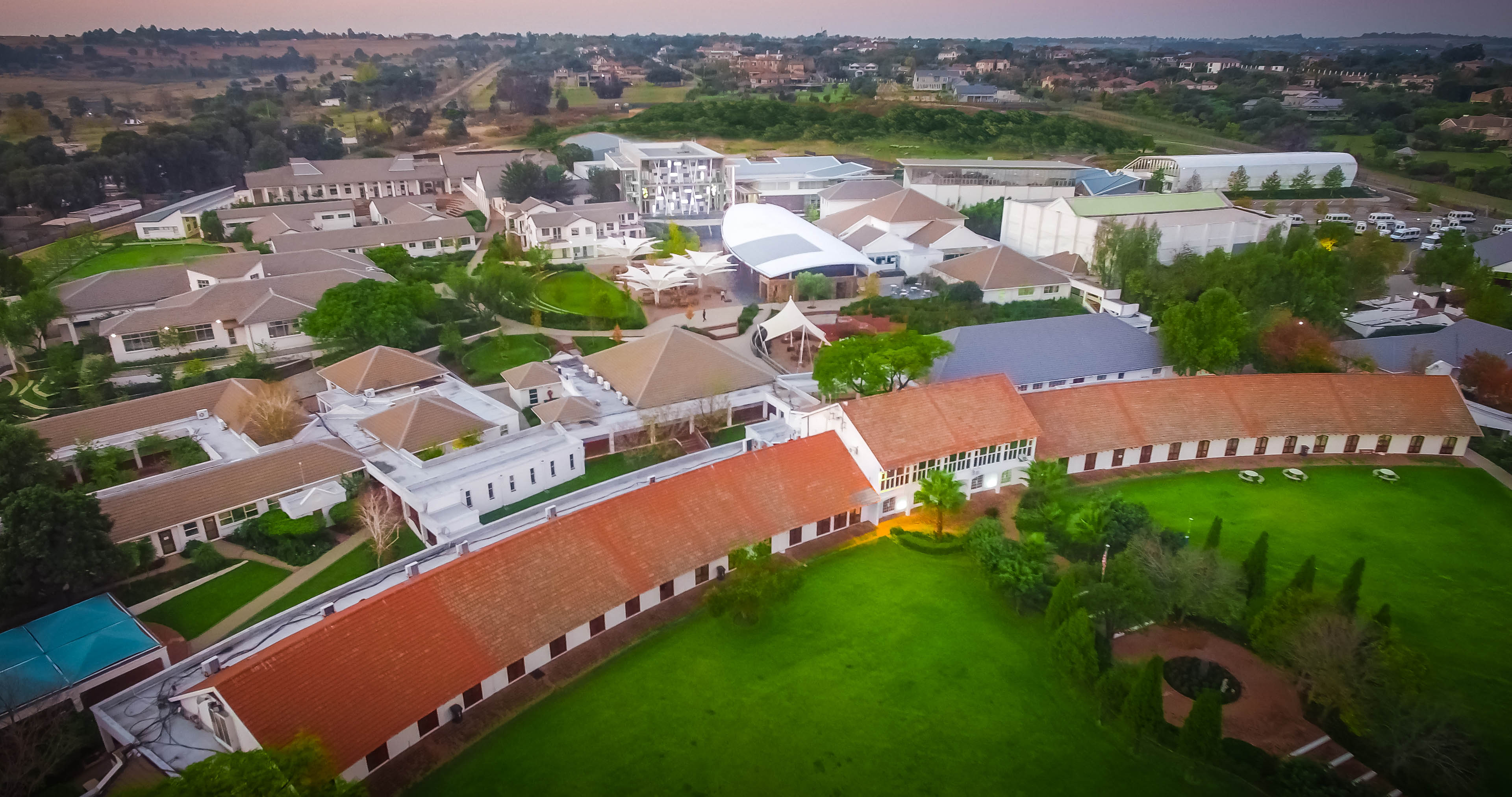 Drone image of building placement, with long building curving in front with large grass area surronding