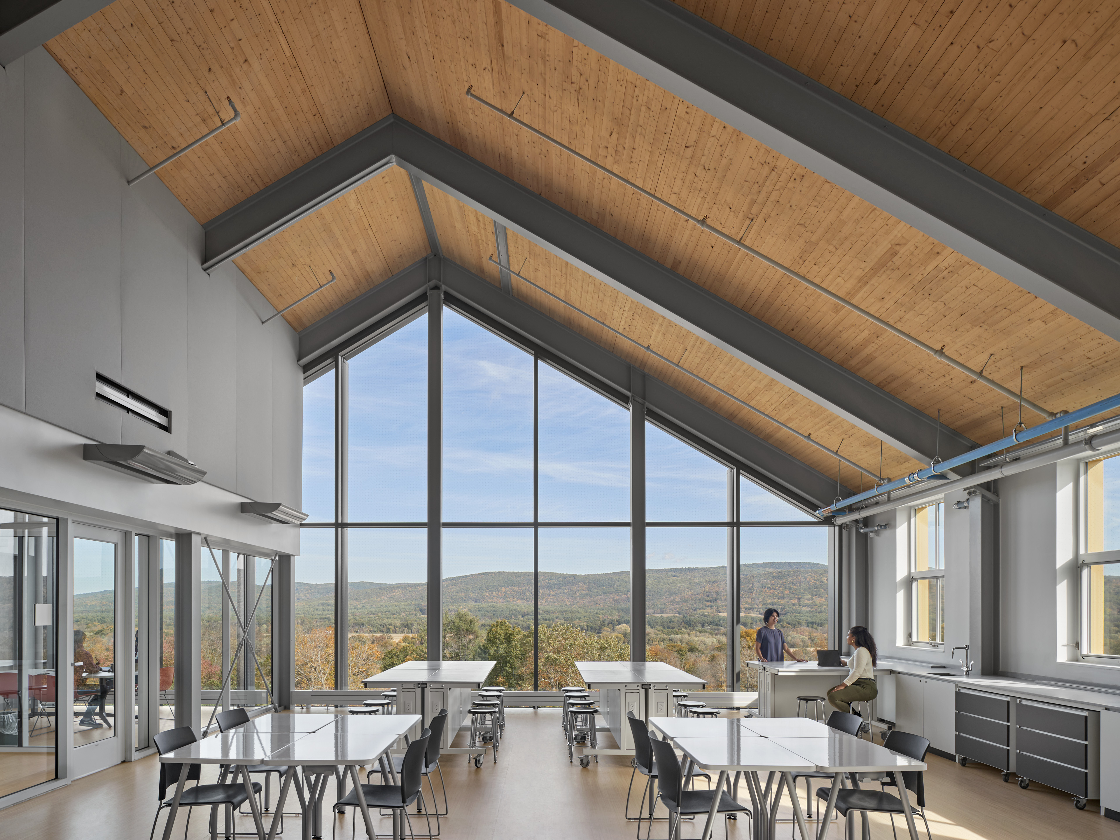 Interior laboratory with 4 lab tables and view of autumn trees with large vertical paned windows and wood paned ceilings