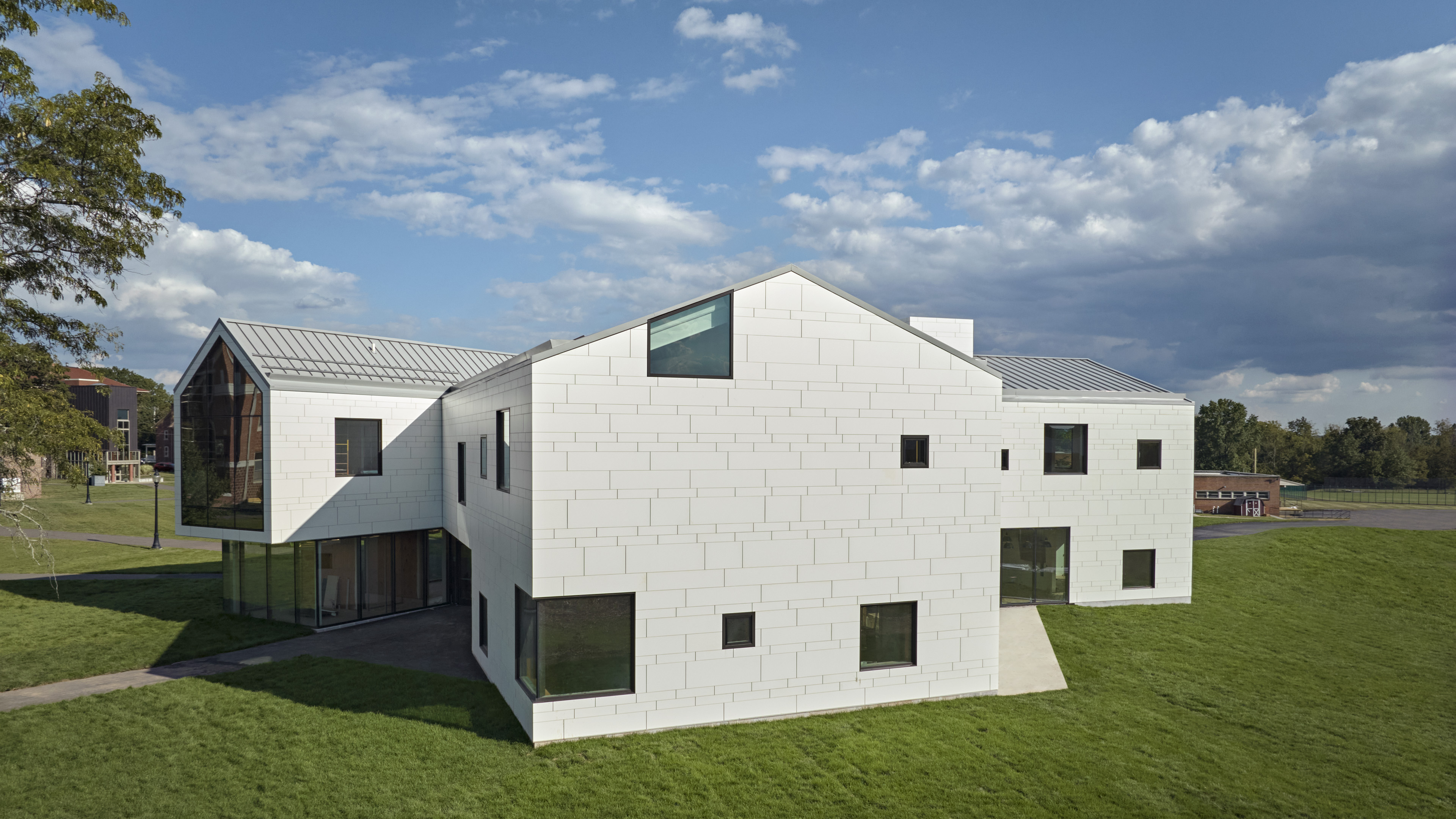 Exterior of student center with barn like structure situated on green grass with blue sky behind
