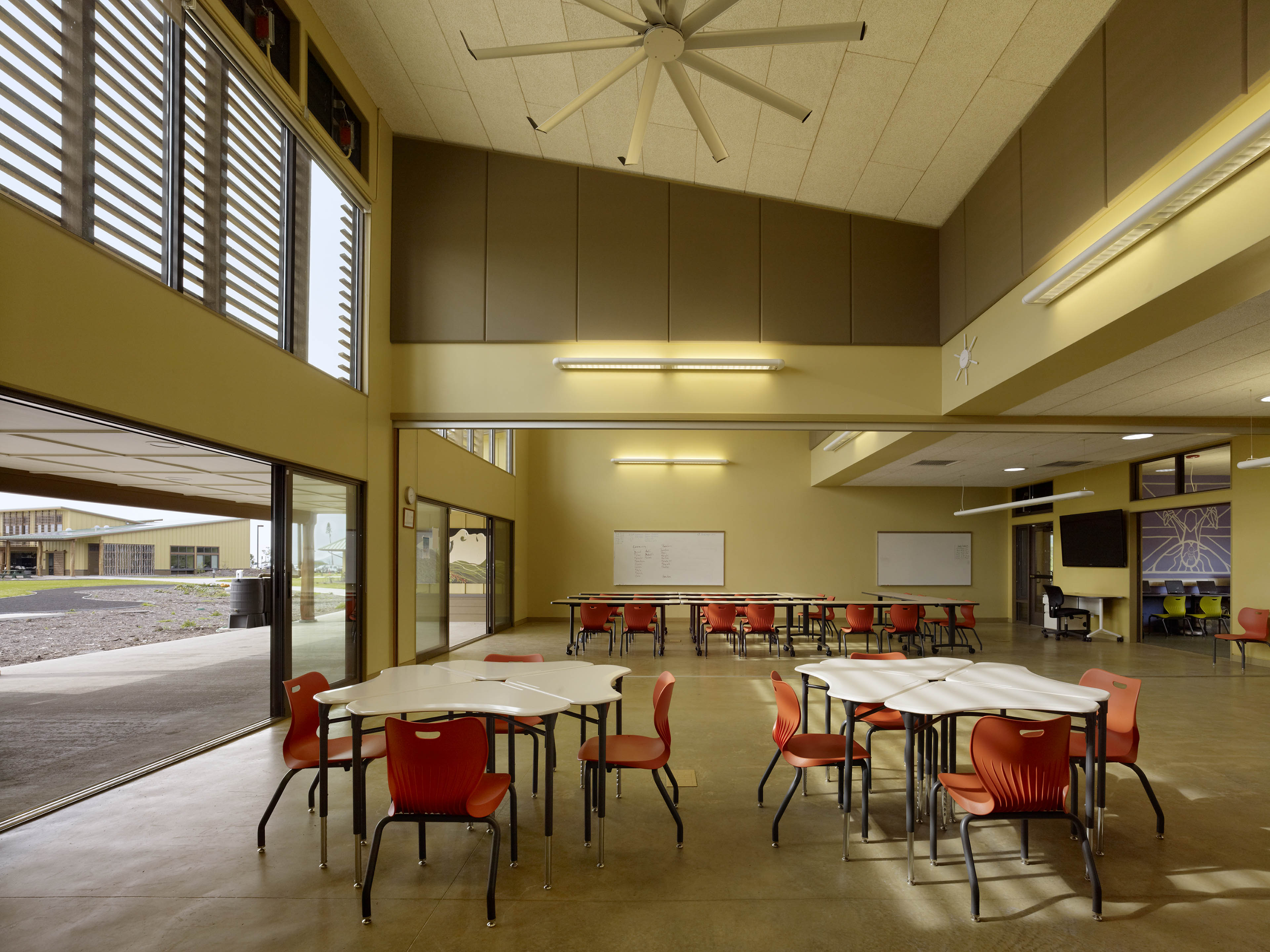 Classroom with clustered seats and open entrance to the left looking out to field