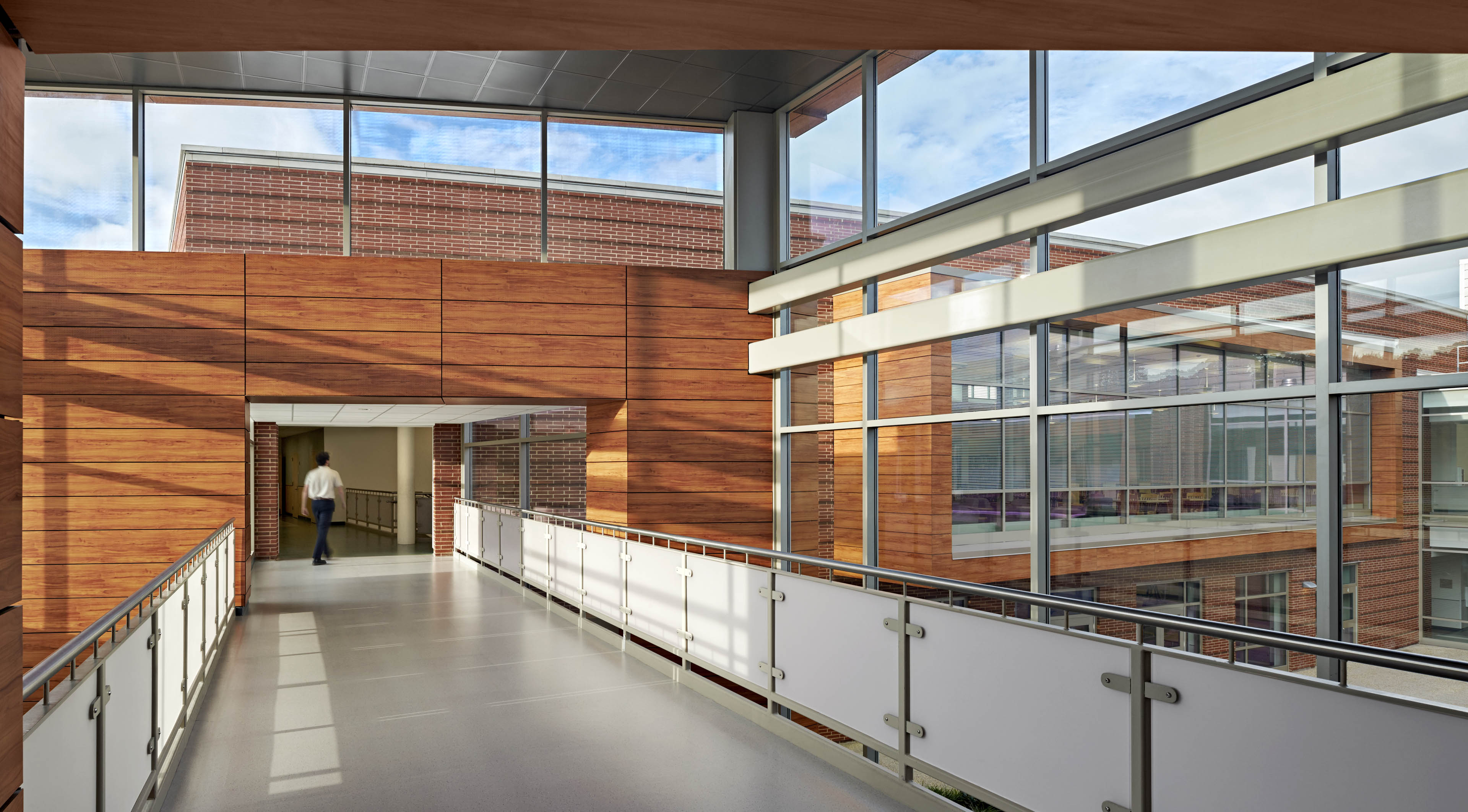 Corridor with wood paneling on back and large windows at the top letting in natural light with blue sky in background