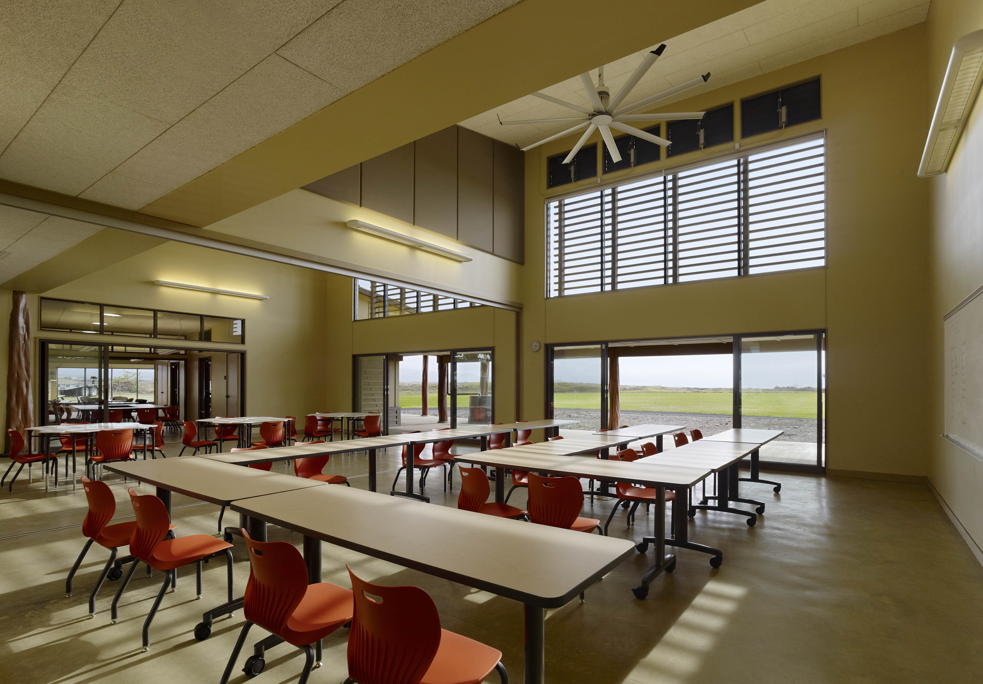 Classroom with long nested tables with open doors looking out at field