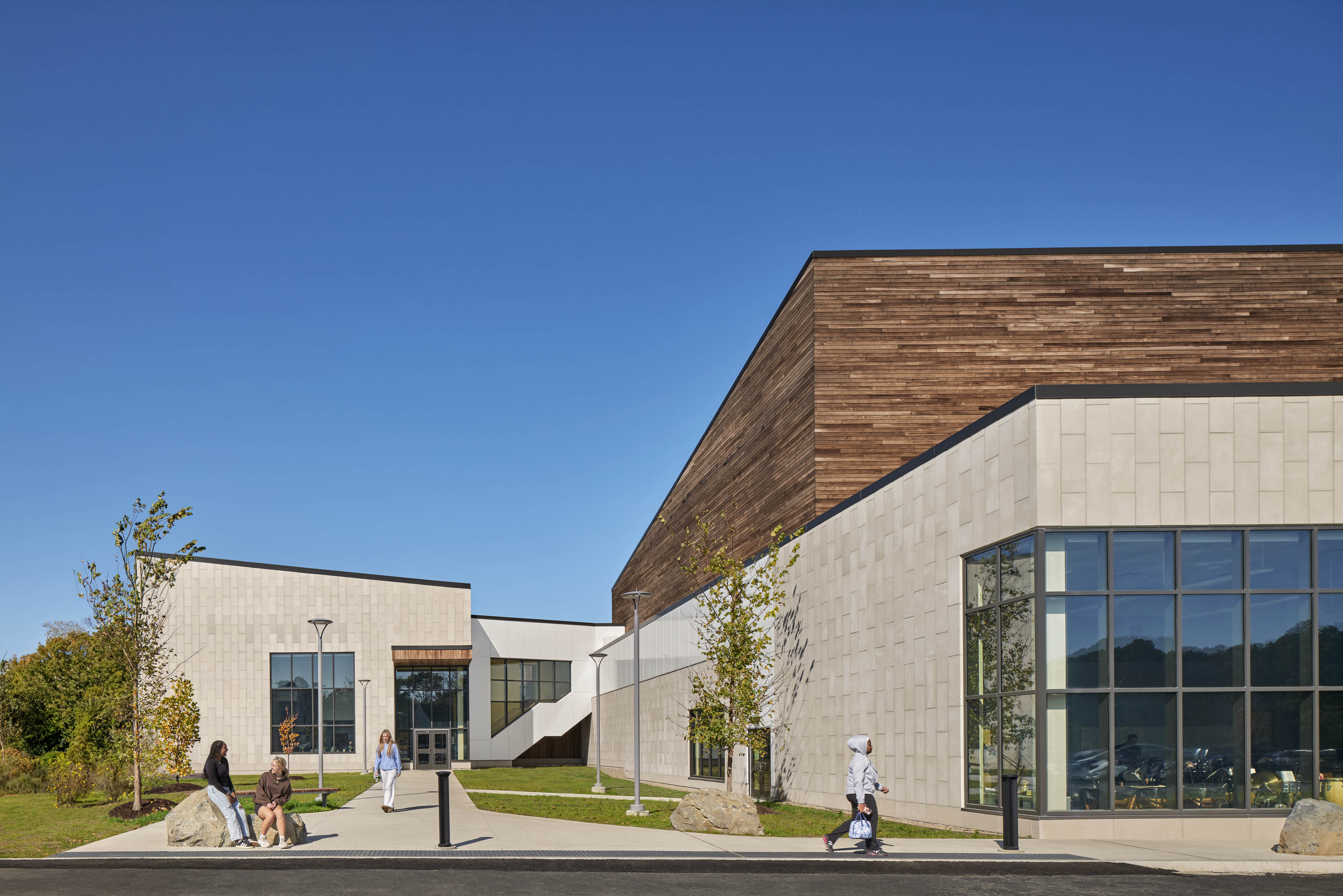 Side entrance of Nauset Regional High School with grey stone on the first level and natural wood continuing up to the second level