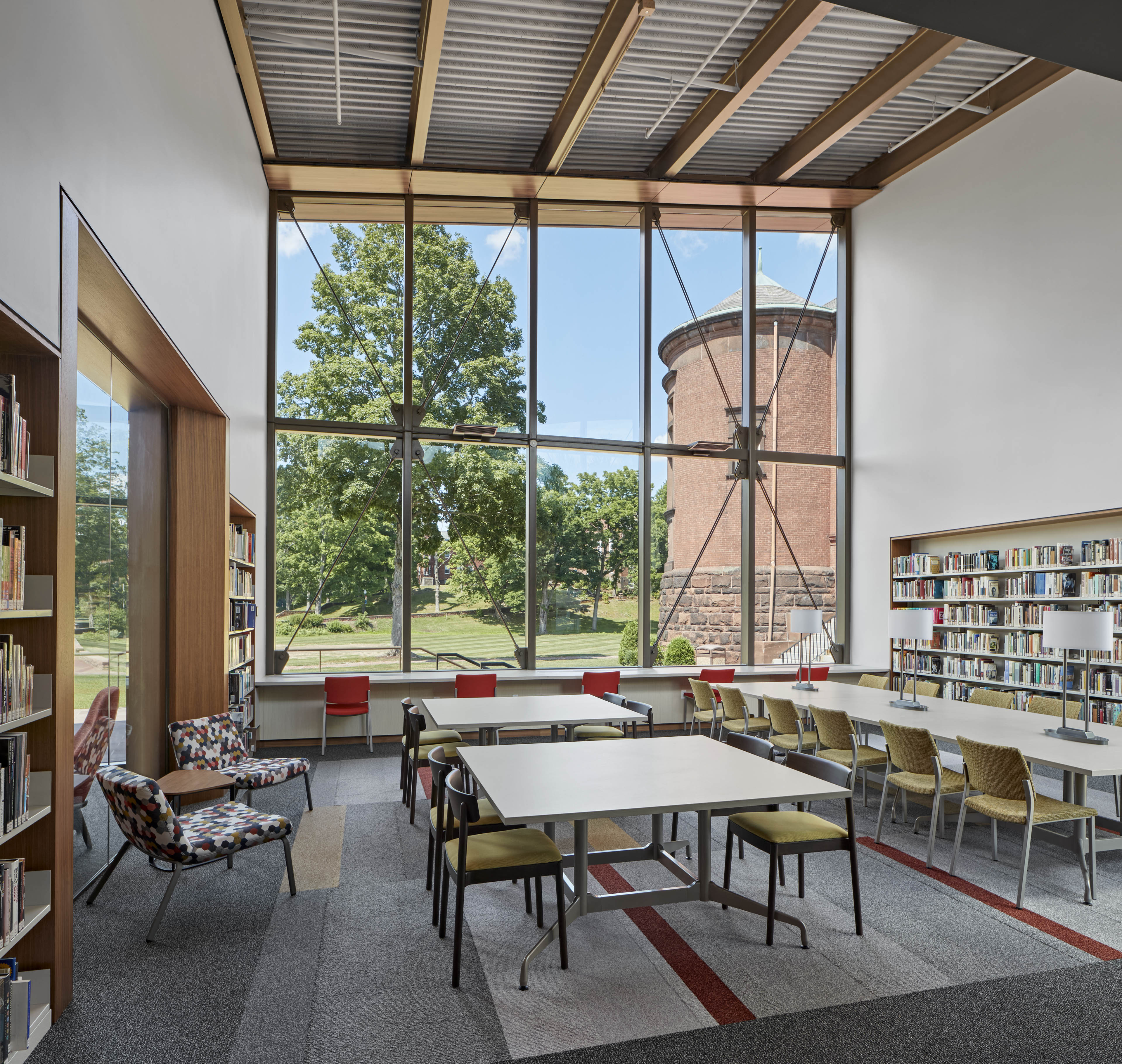 Library wit windows in center looking out to grassy area. Book shelves on left and right side