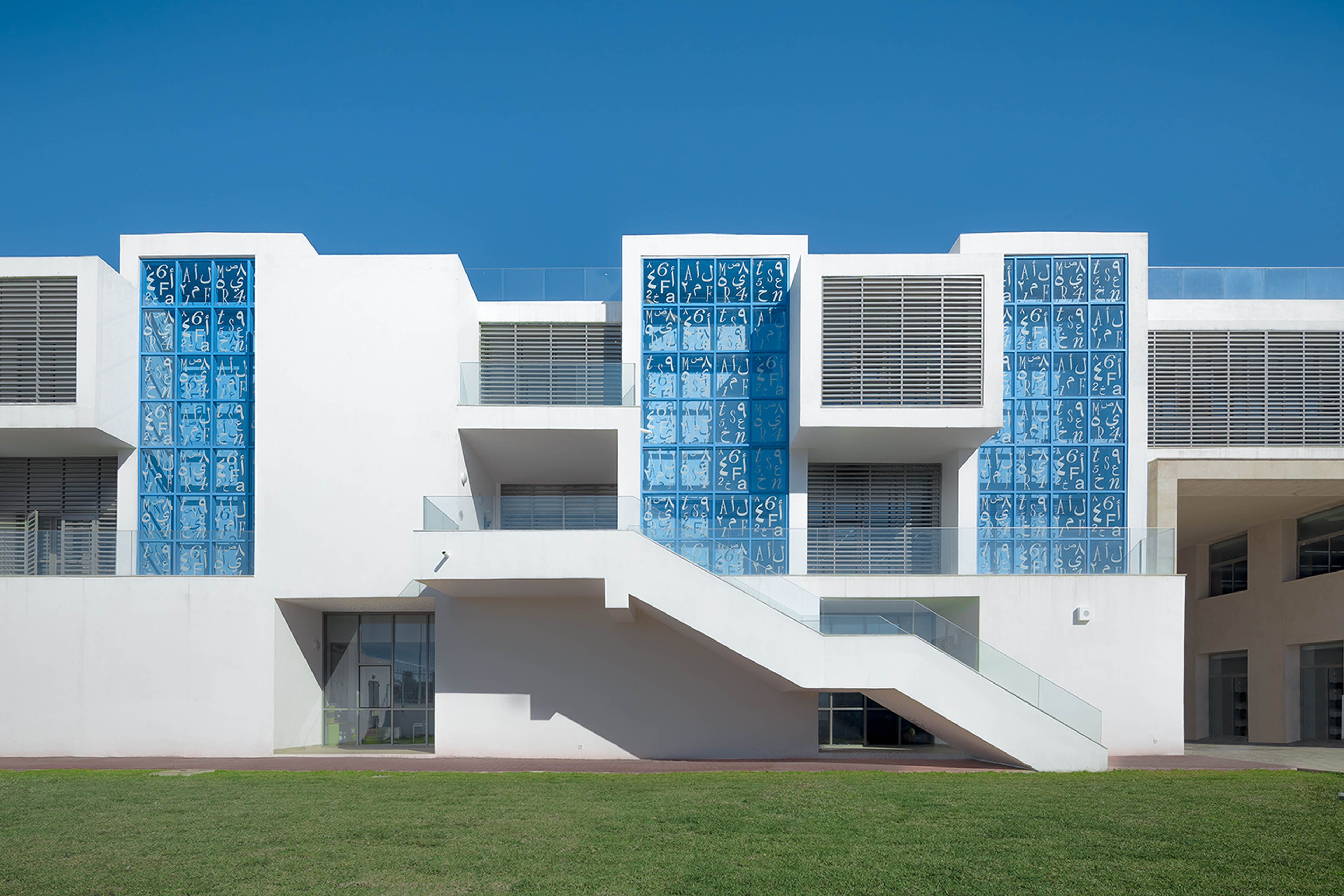 White building with light blue windows and green grass in front