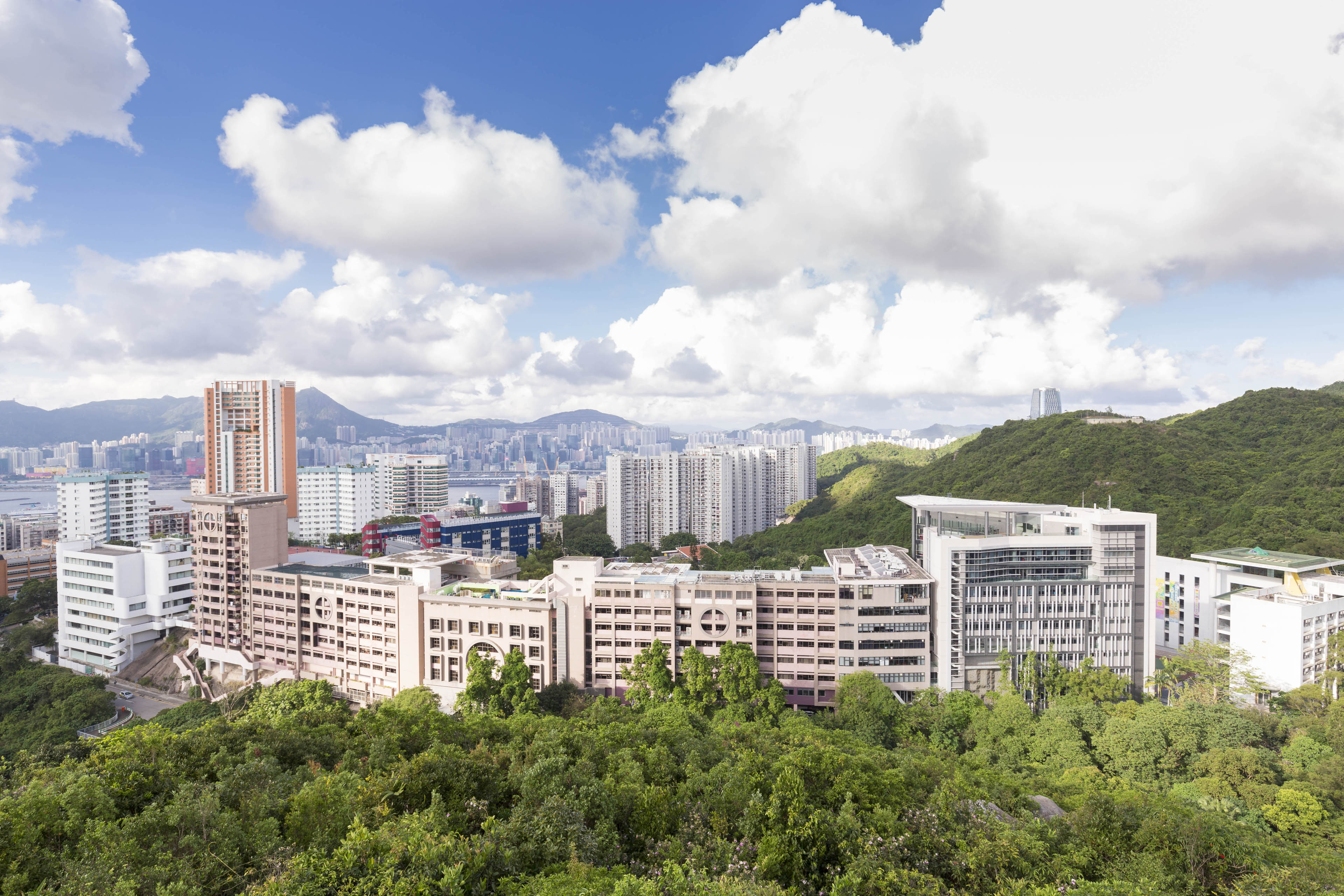 View of building nestled into the city with trees and rolling hills surronding