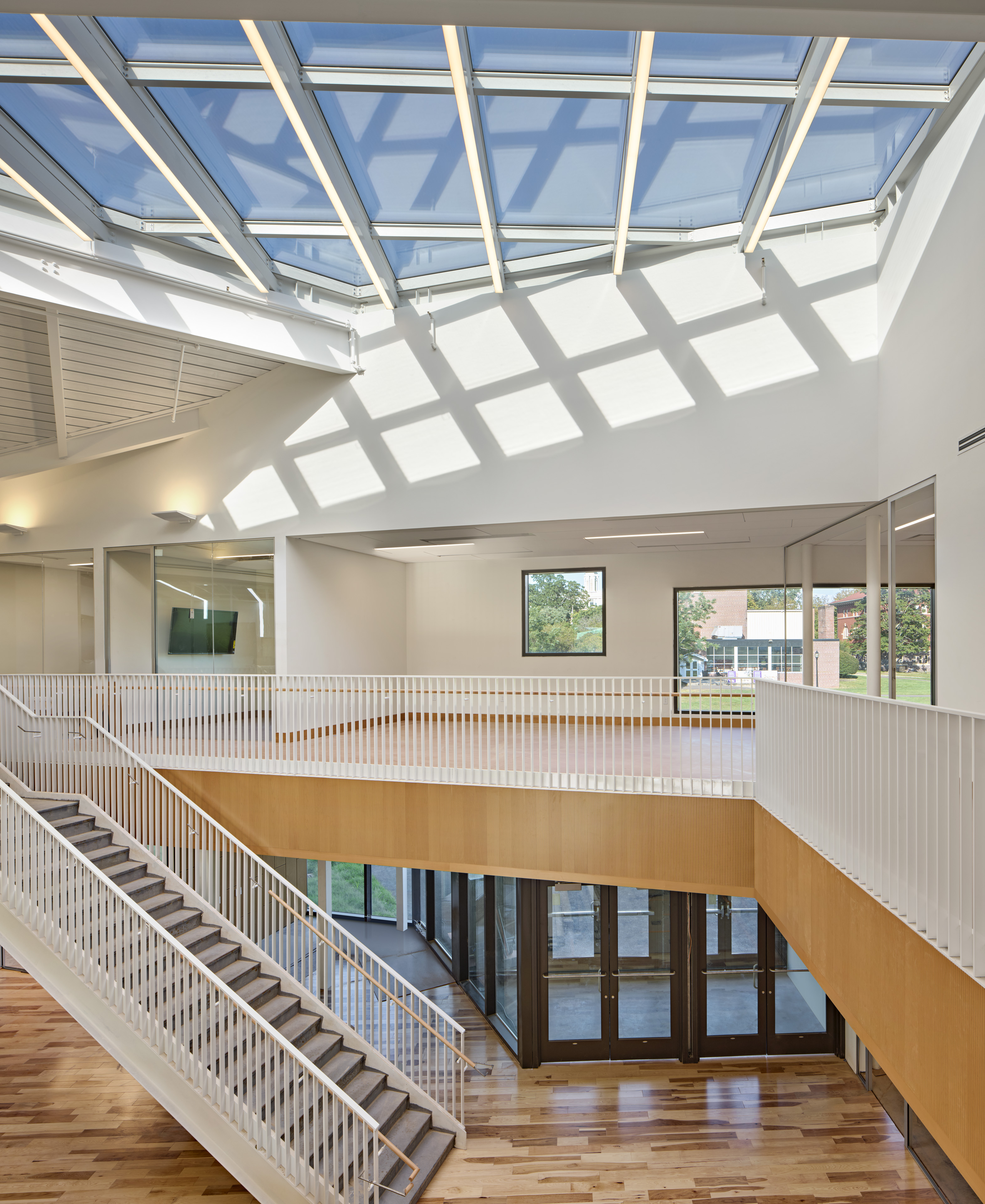 Interior staircase with white walls and window panes on ceilings and light brown wood