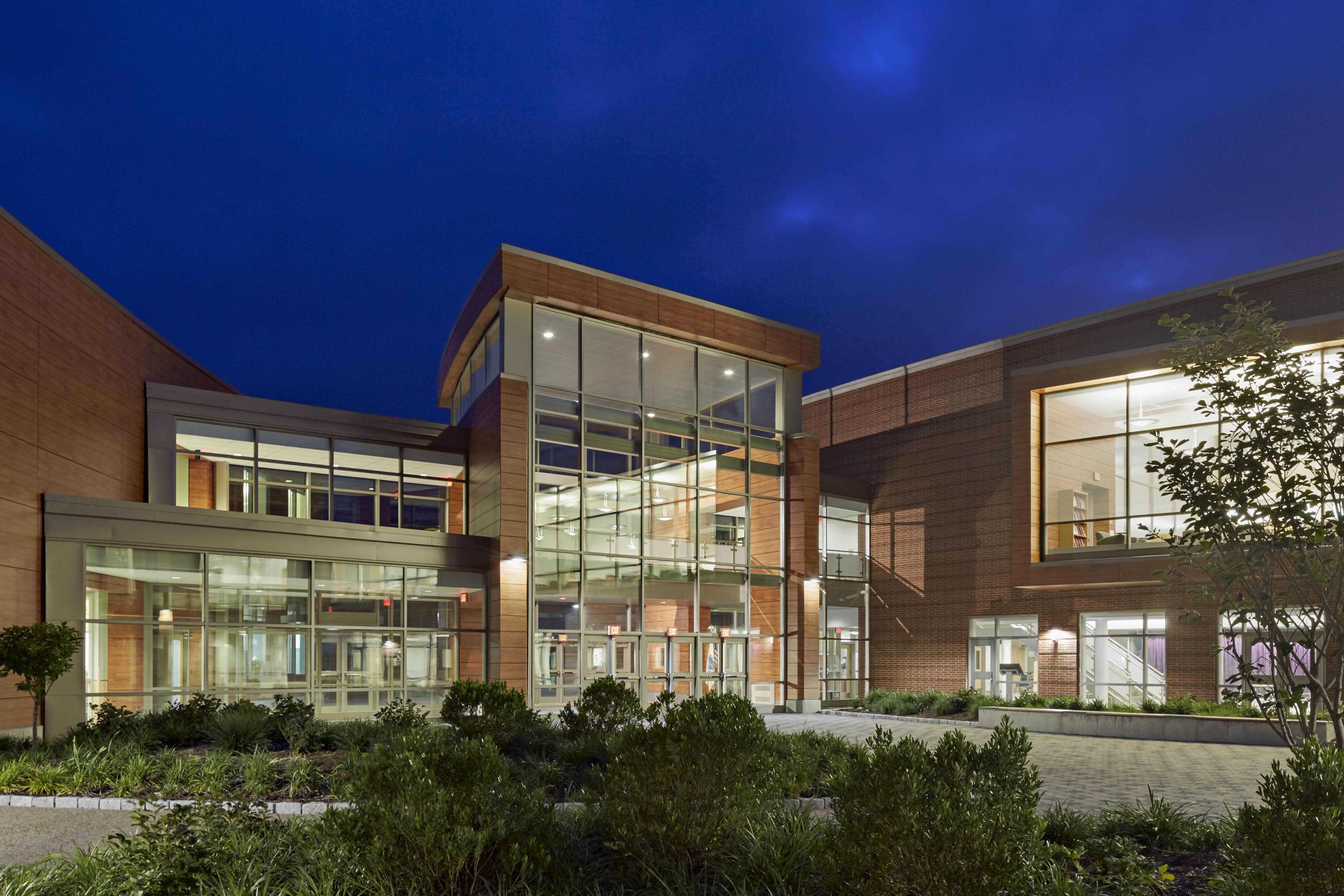 Entrance of school at night with deep blue sky behind and greenery in front