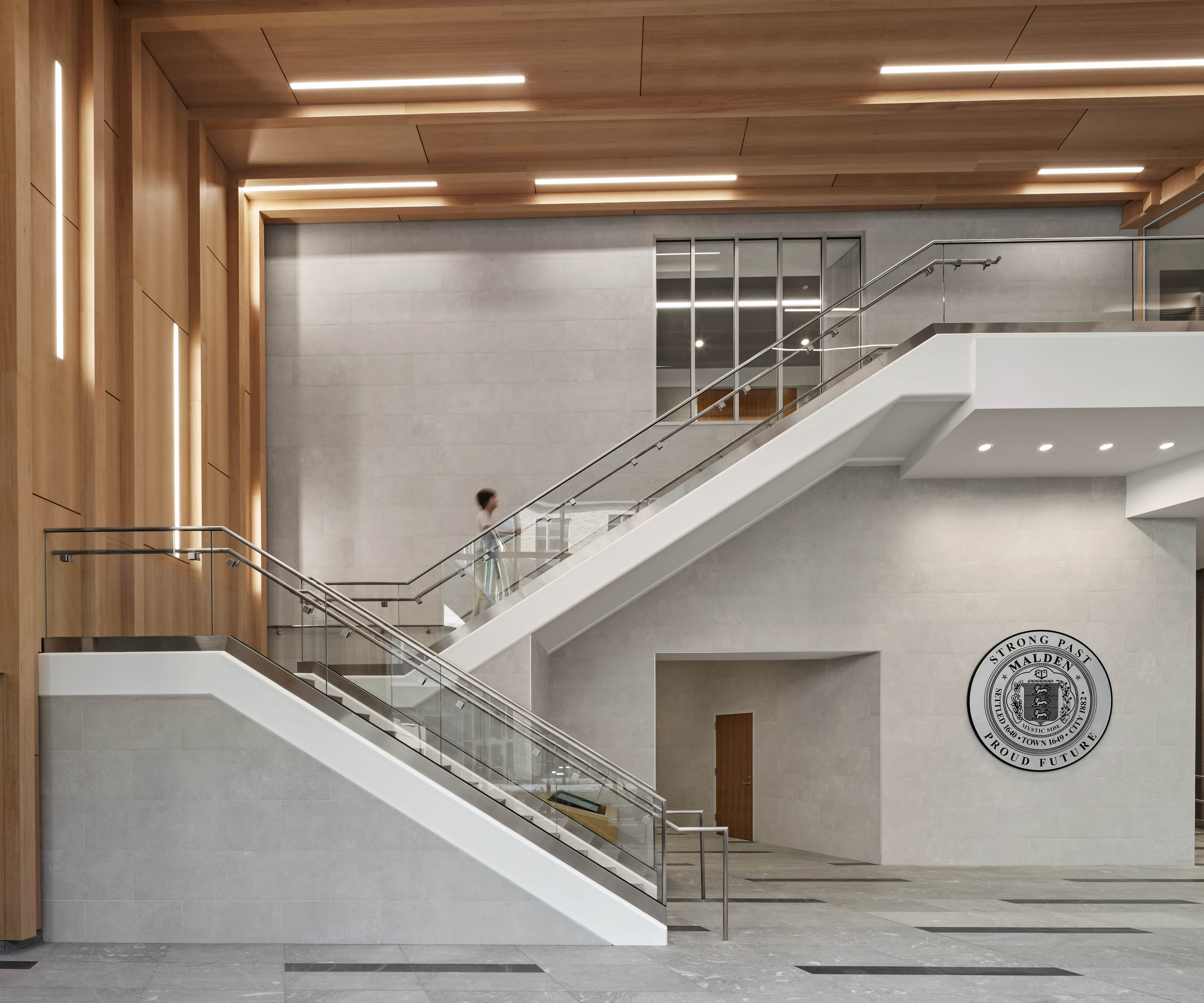 Interior staircase with light wood covering wall to the left and town crest on wall to the right